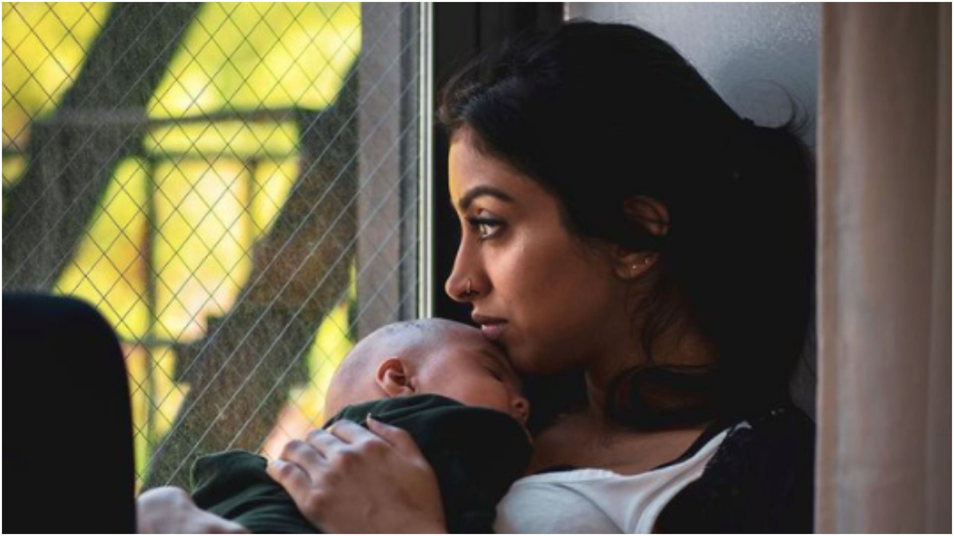 Nikita Singh holds her baby and looks out the window 