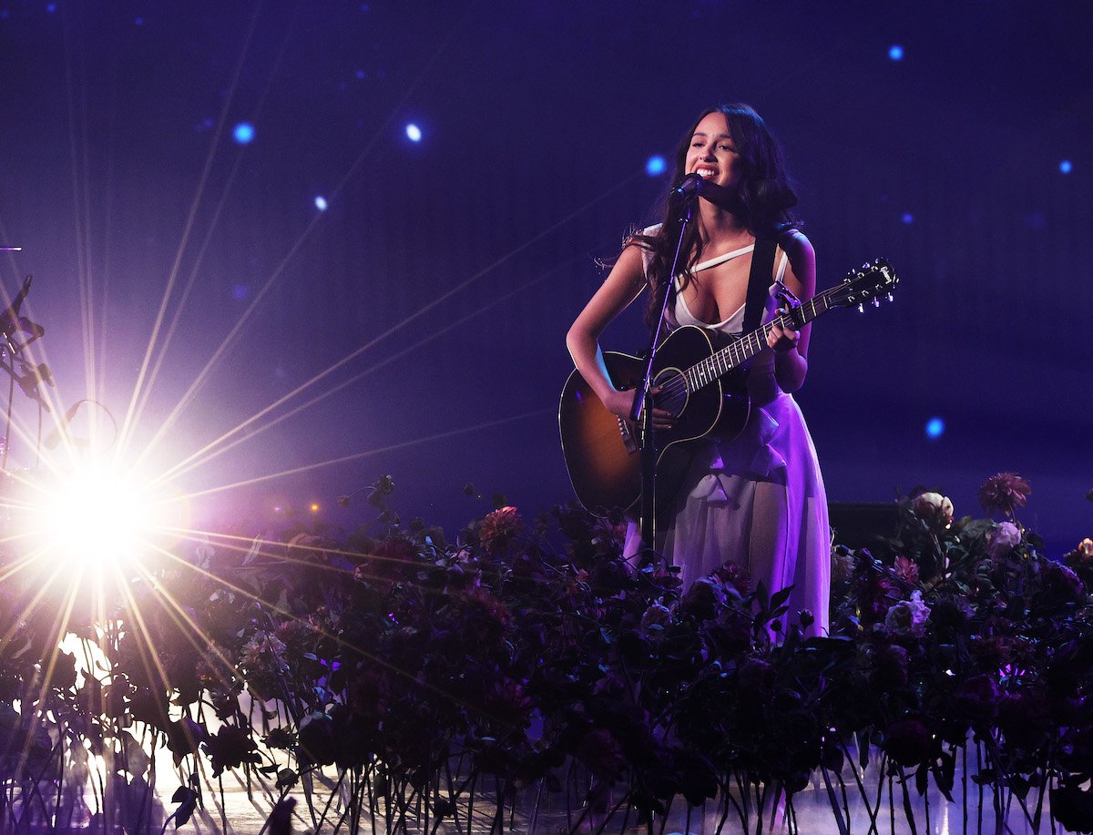 Olivia Rodrigo performs on stage with a guitar.