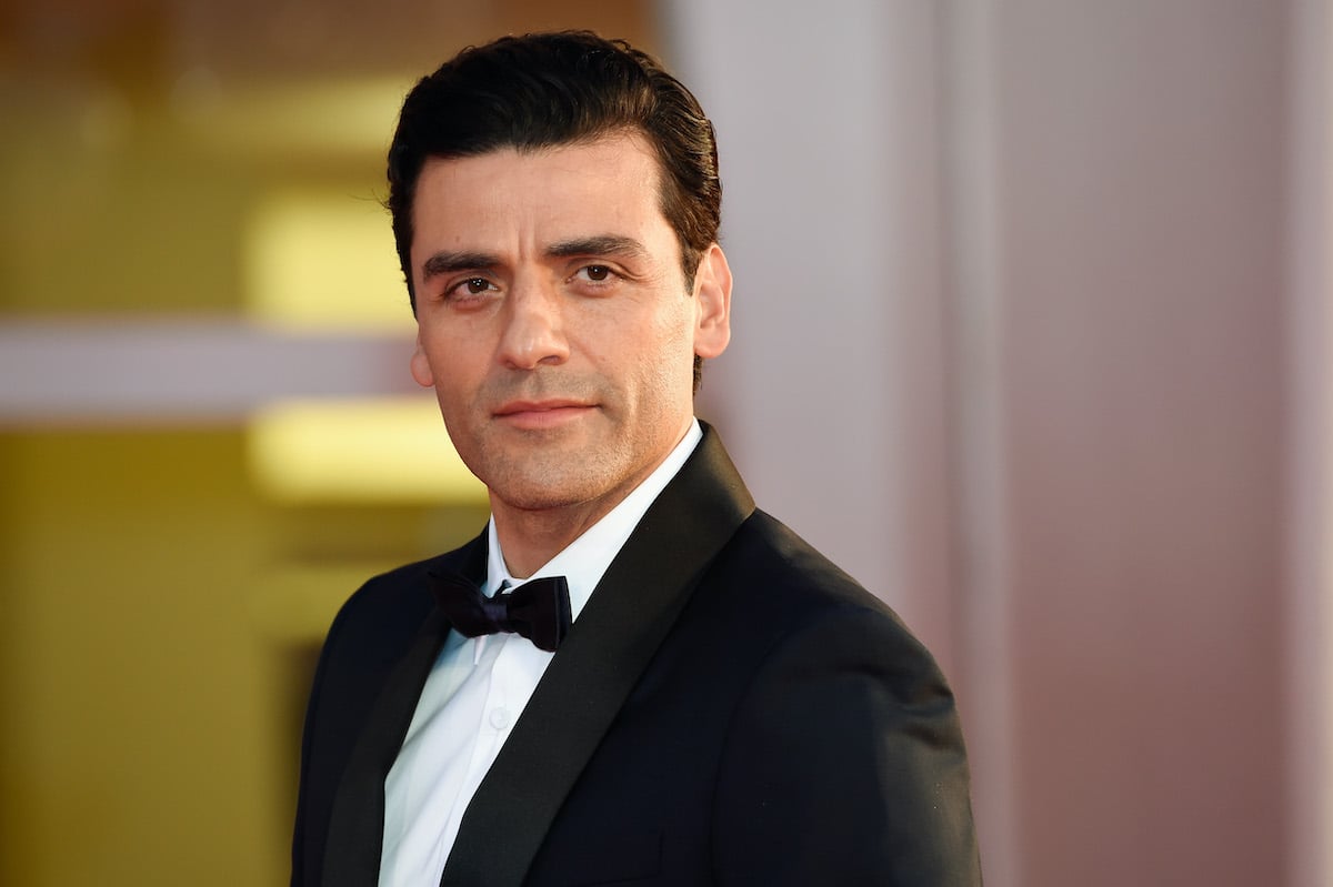 Oscar Isaac smiles in a dark suit on the red carpet