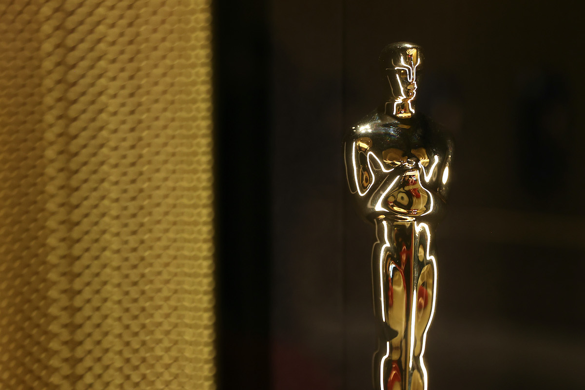 An Academy Award stands next to a gold curtain