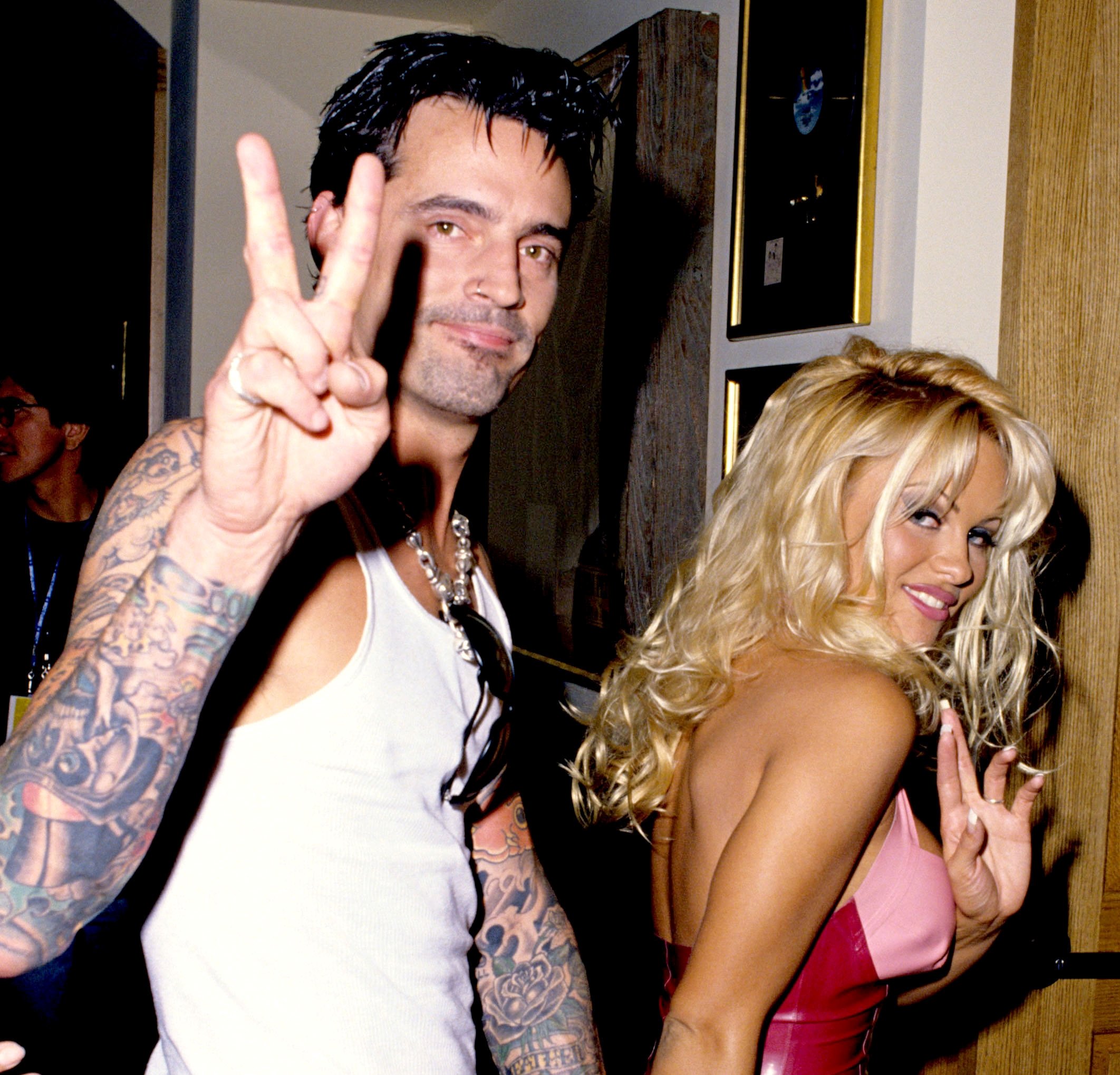 Pamela Anderson and Tommy Lee smiling and waving to the cameras during a hotel opening in Las Vegas