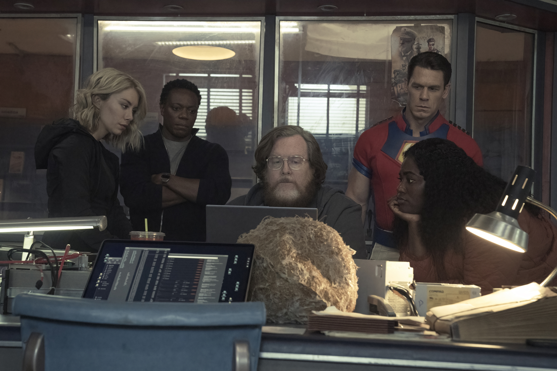 Jennifer Holland, Chukwudi Iwuji, Steve Agee, John Cena, and Danielle Brooks in DC's 'Peacemaker' Episode 6. They're all gathered around a computer.