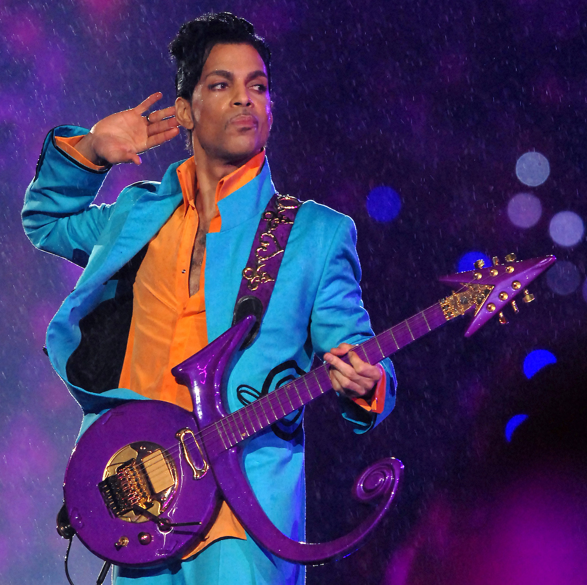 Prince performs at the Super Bowl with a purple guitar.