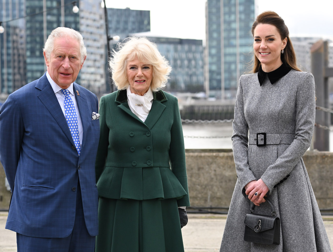 Prince Charles, Camilla Parker Bowles, and Kate Middleton looking on in front of a skyline