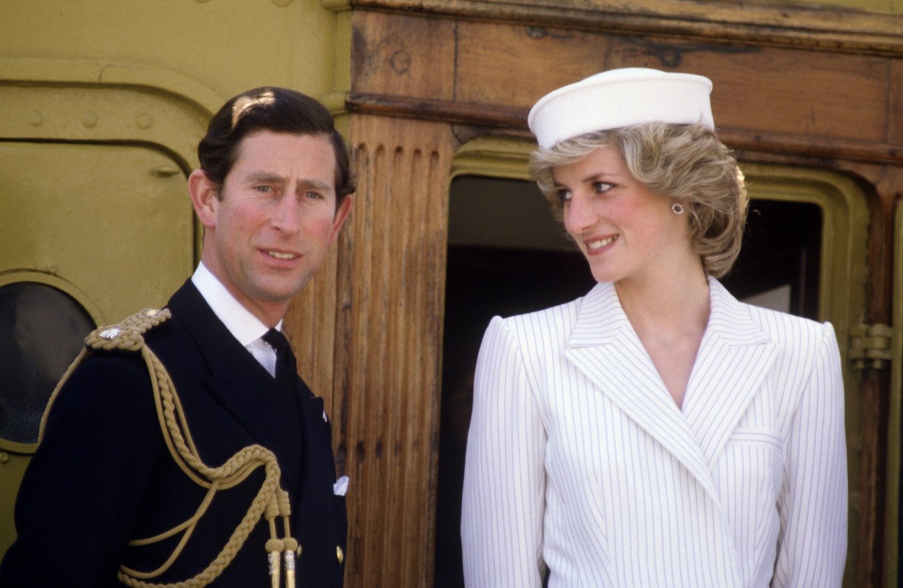 Prince Charles wearing a black suit and Princess Diana wearing a white outfit with a sailor's hat