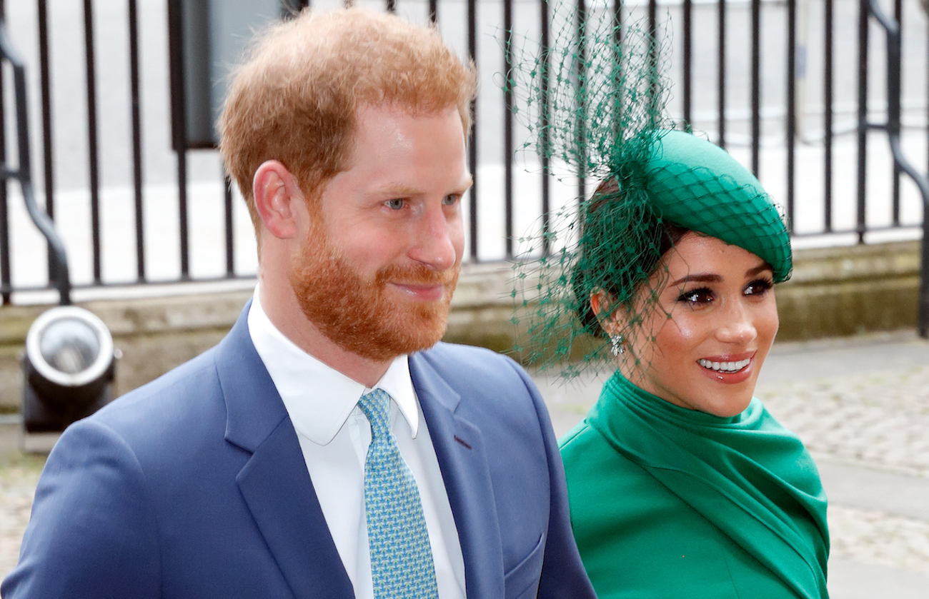 Prince Harry and Meghan Markle walk side by side wearing blue and green