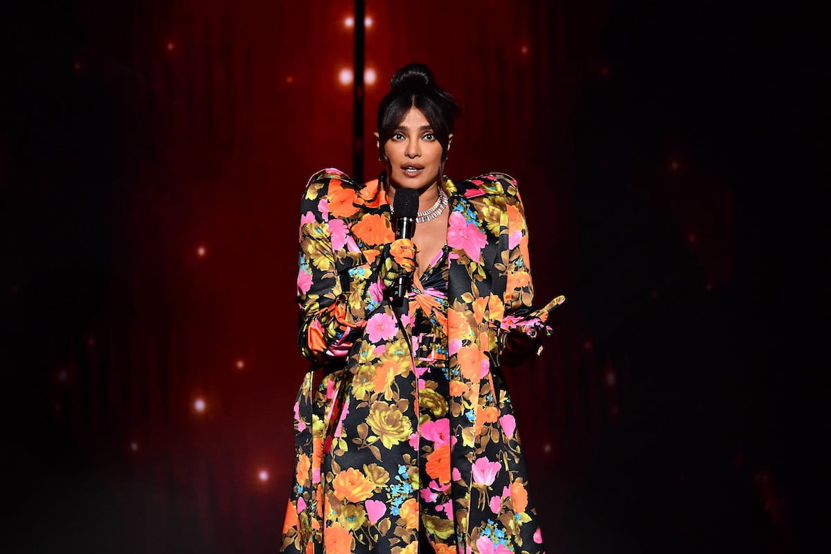 Actor Priyanka Chopra Jonas wears a brightly colored floral dress while speaking on stage during The Fashion Awards 2021