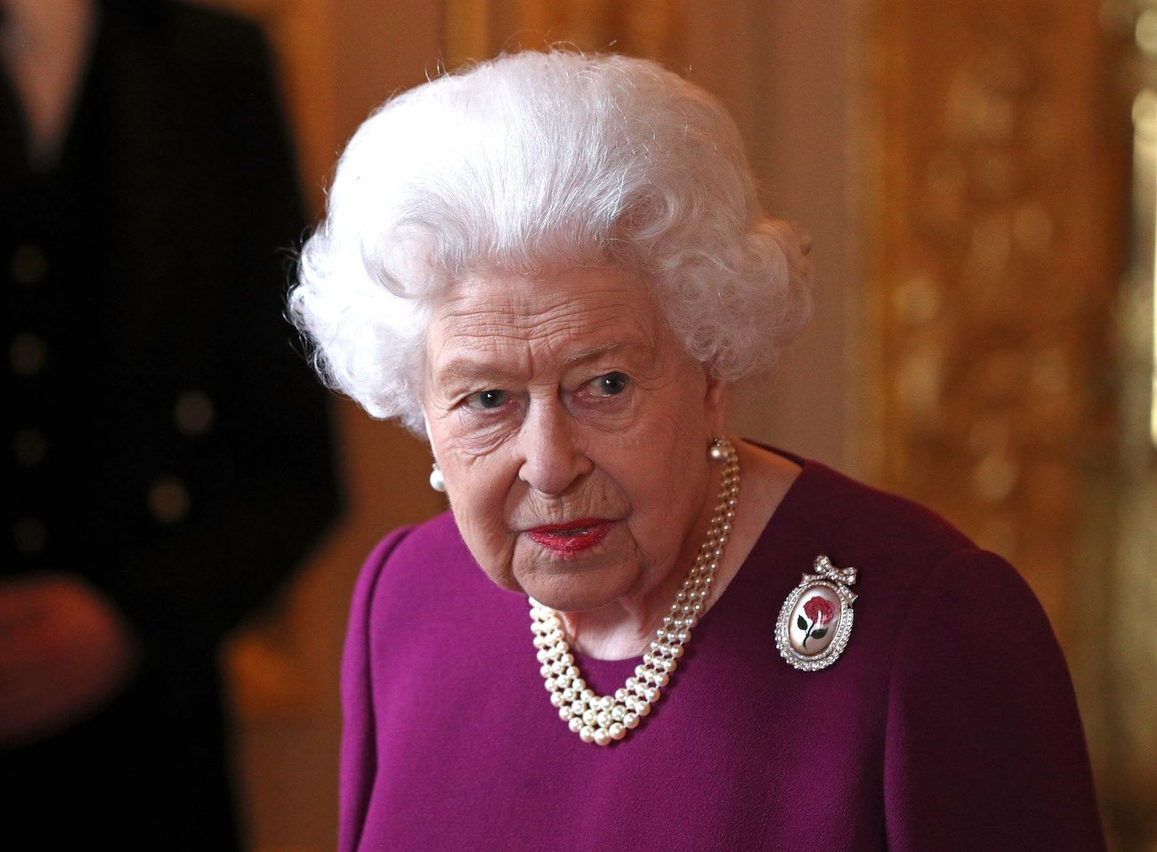 Queen Elizabeth looking on while wearing a magenta outfit