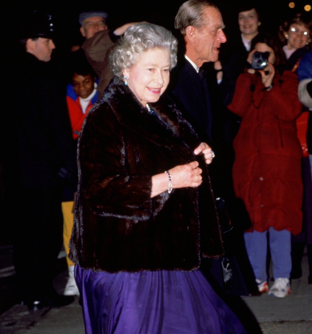Queen Elizabeth II wearing a fur coat as she leaves a dinner party in Grosvenor Square