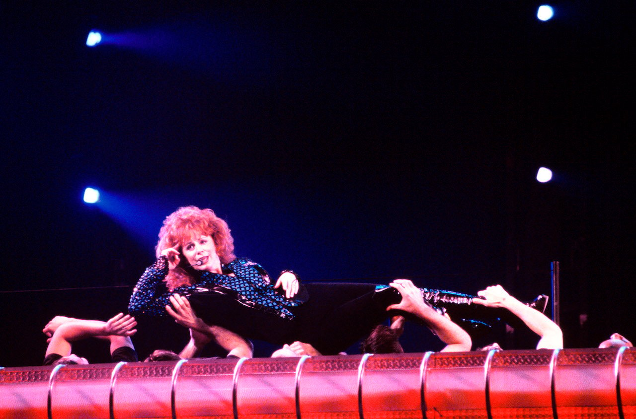Reba McEntire performs while being held by dancers during a concert in 1995