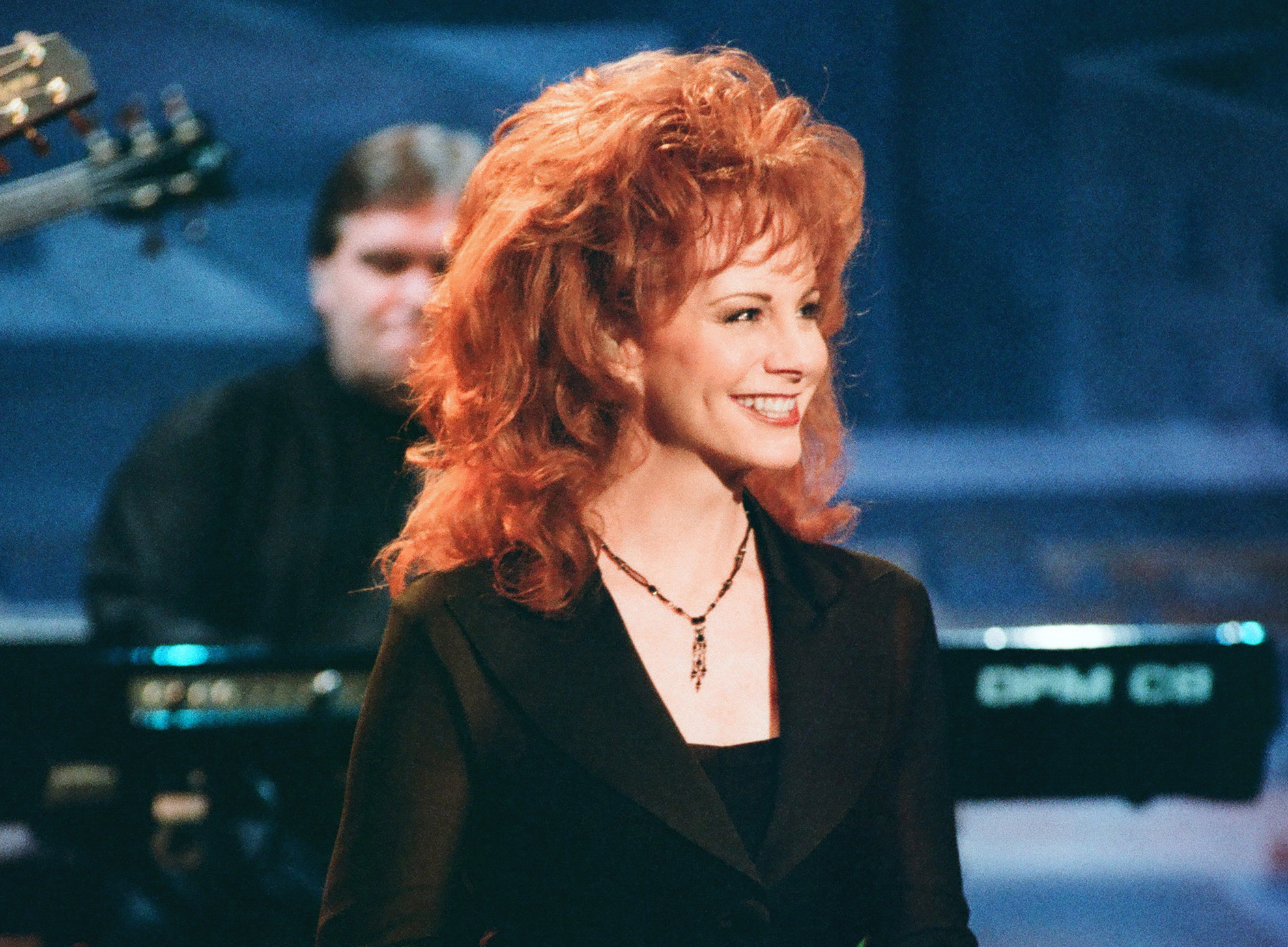 Reba McEntire smiles at an audience, dressed in a black dress and performing on 'The Tonight Show' in 1995