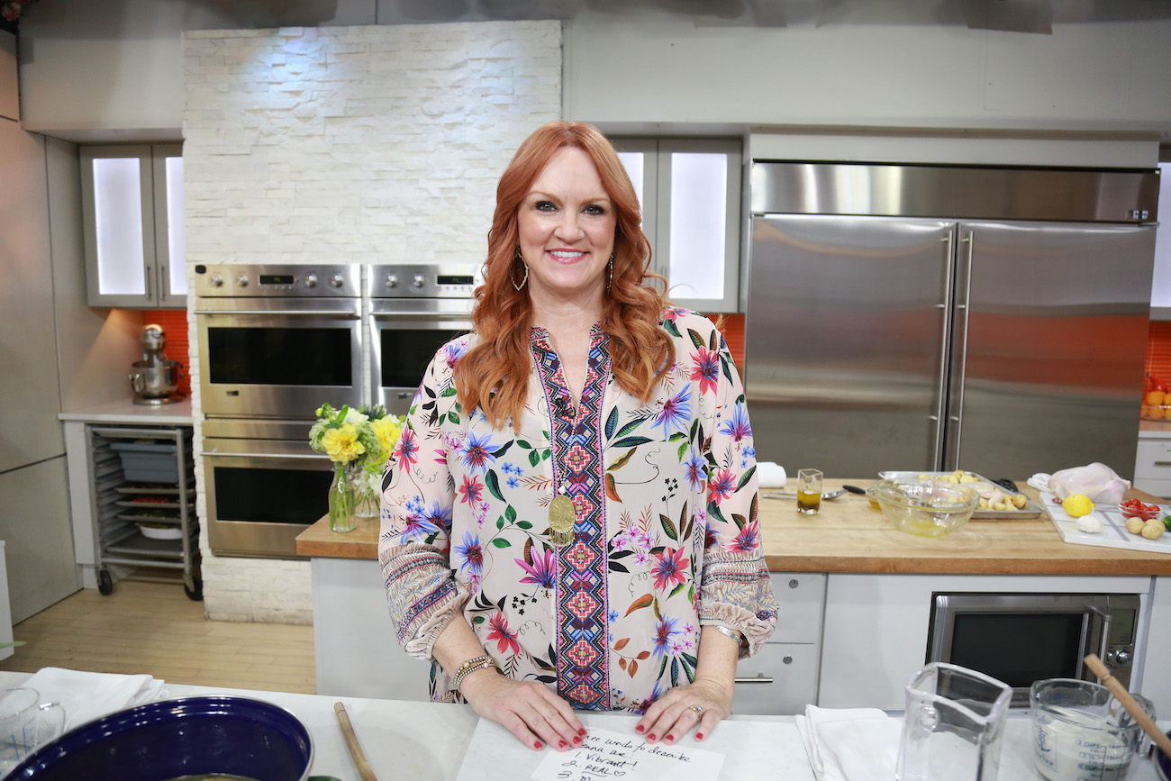 Ree Drummond smiles wearing a multicolor top while standing at a kitchen counter