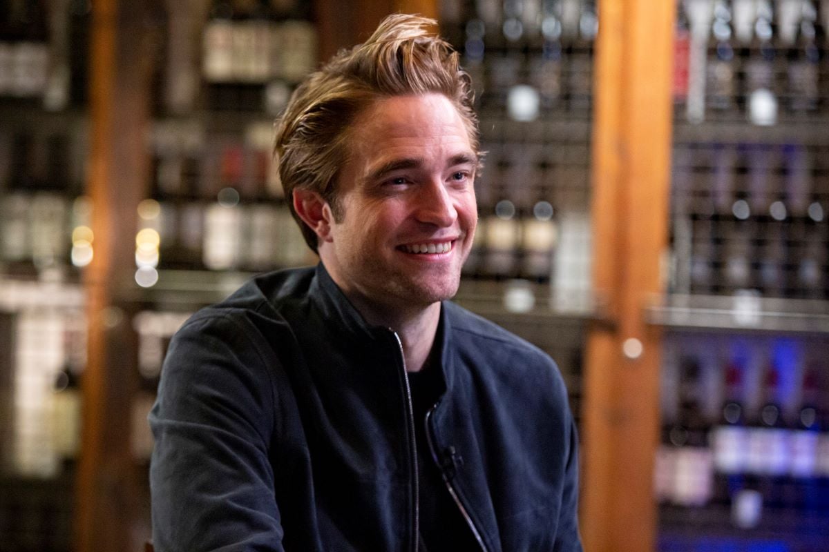 Robert Pattinson smiling in a blue jacket