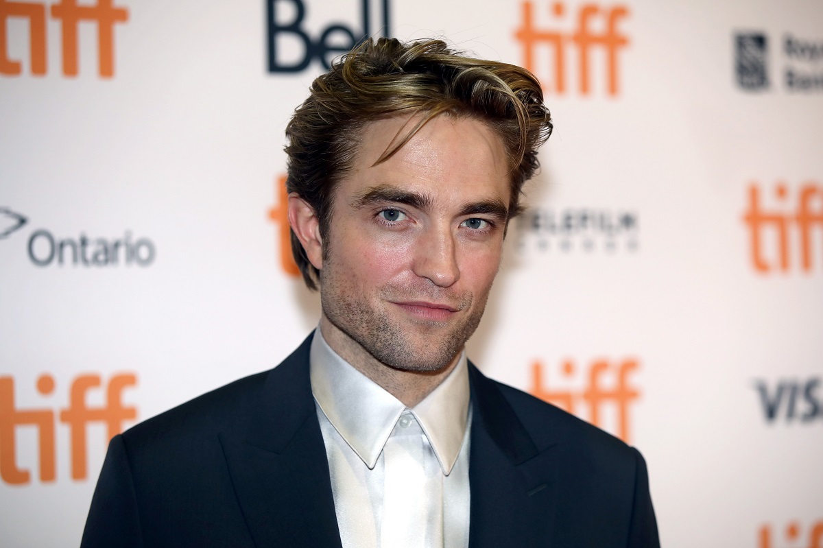 Robert Pattinson smirking while wearing a suit.