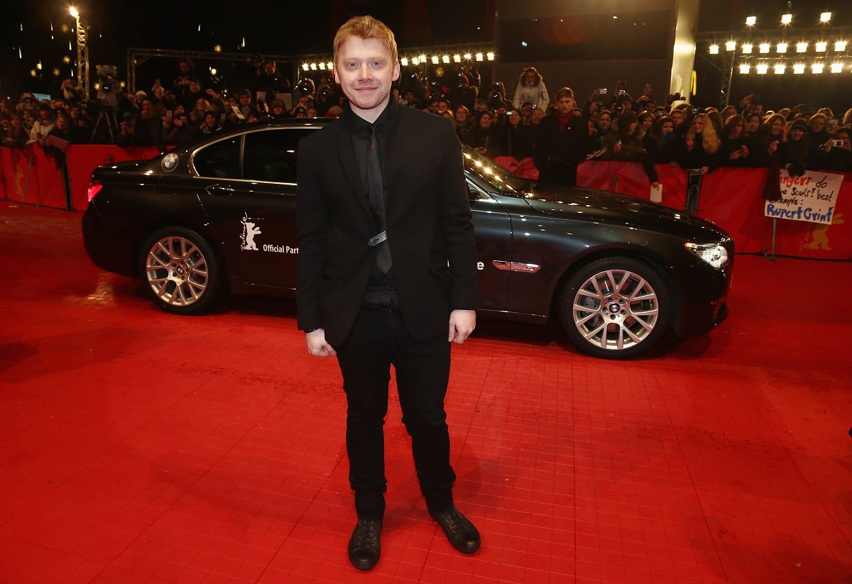 Rupert Grint smiling while wearing a suit.