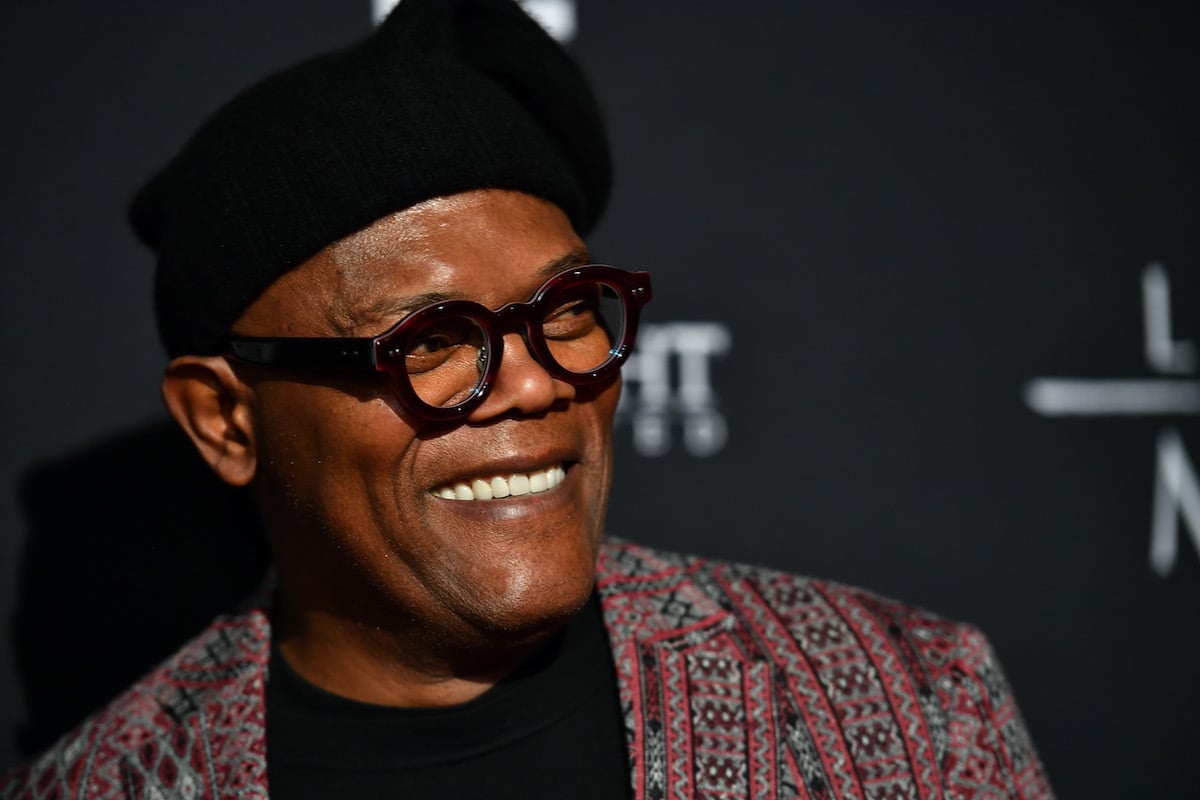 Samuel L. Jackson wears a dark hat and glasses as he smiles