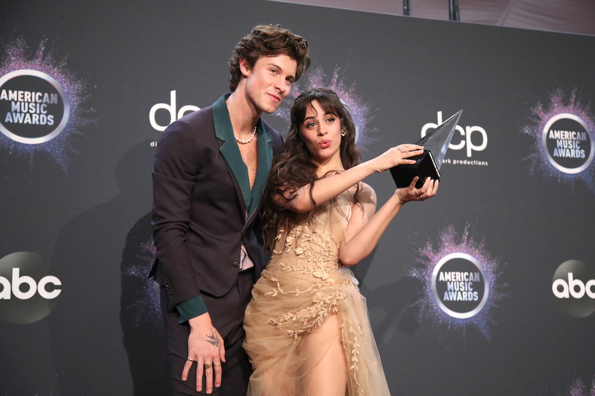 Shawn Mendes and Camila Cabello pose together holding an award at an event.