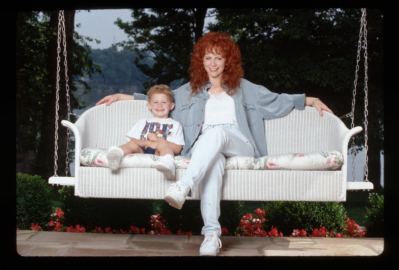 Country singer Reba McEntire and her young son Shelby relax on a porch swing c. 1994.