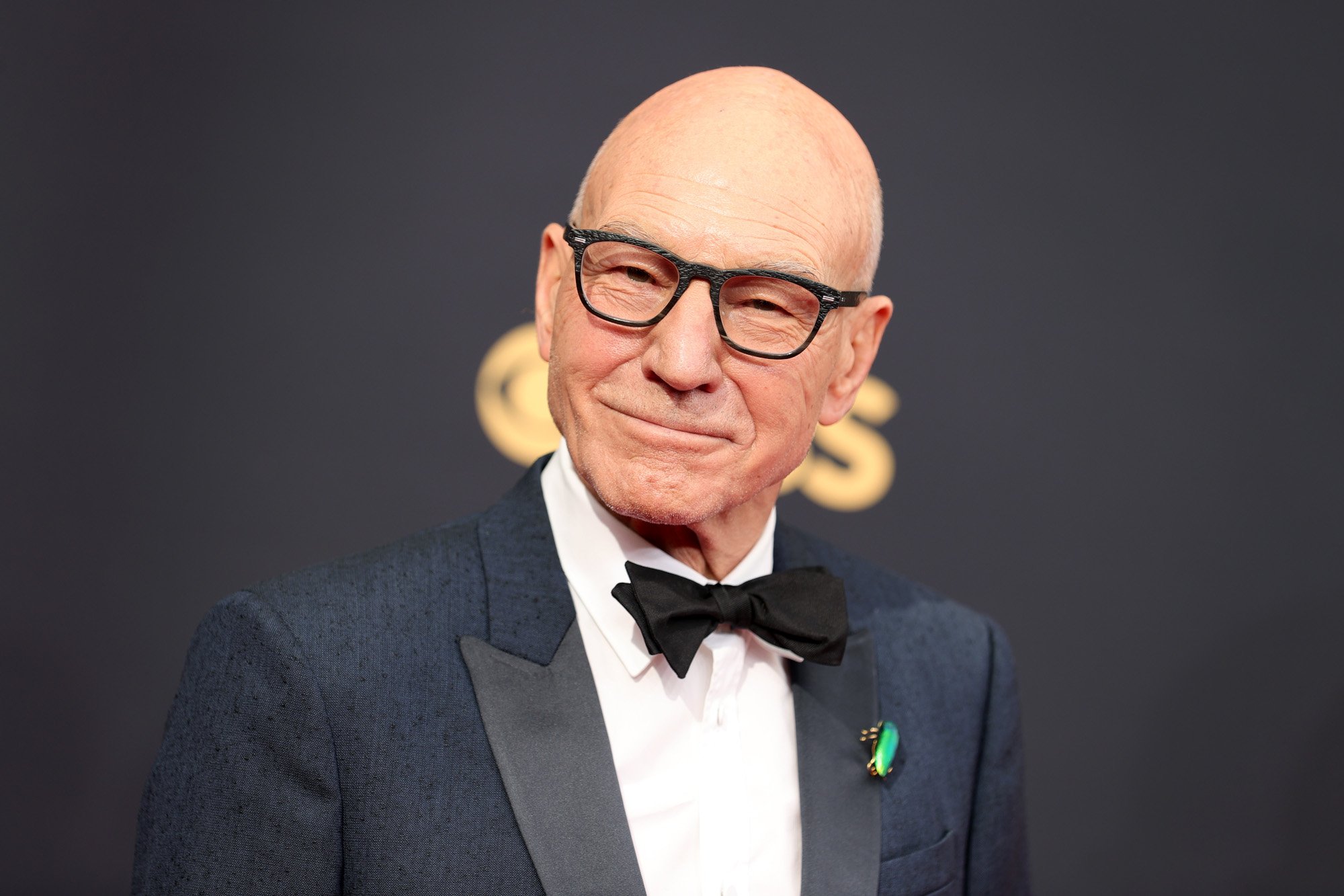 Professor X actor Sir Patrick Stewart wearing glasses, a black suit, and a black bowtie.