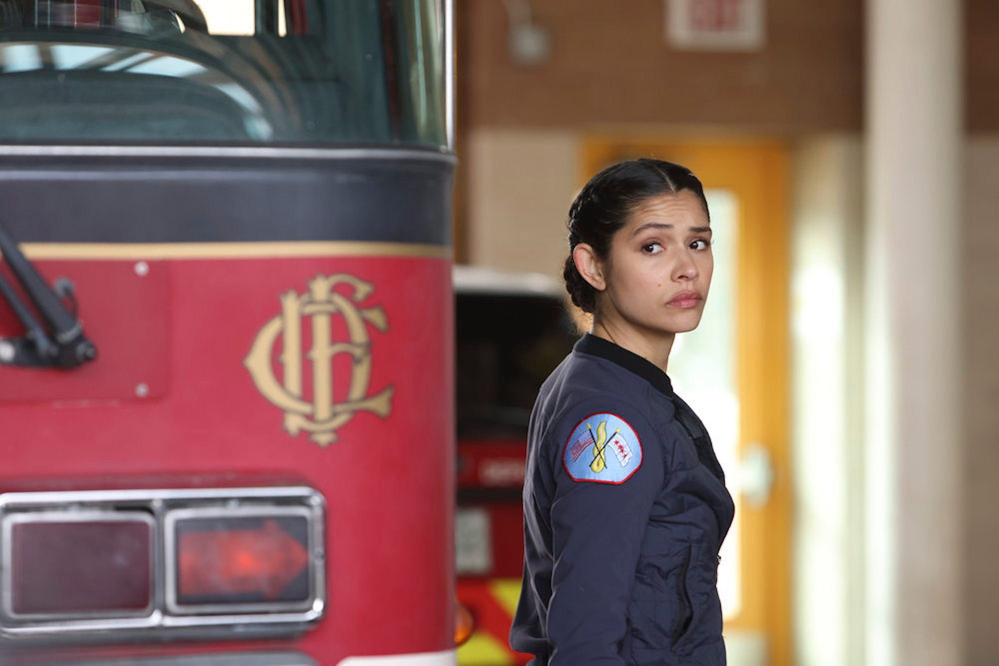 Miranda Rae Mayo as Stella Kidd looking over her shoulder next to a fire truck in 'Chicago Fire' Season 10