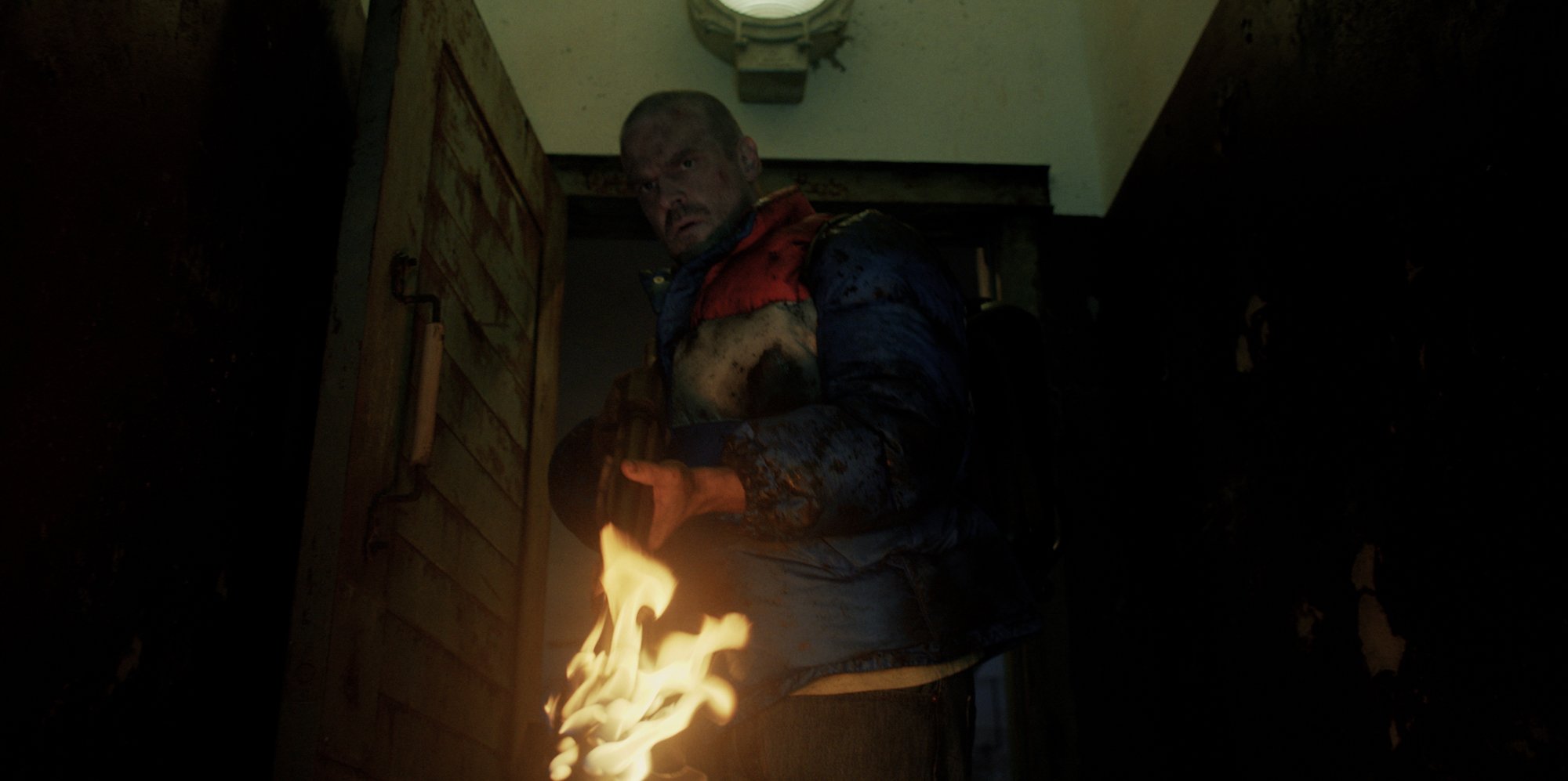 Chief Jim Hopper holds a blow torch in a production still for 'Stranger Things 4.' A full-length trailer for the season has yet to debut.