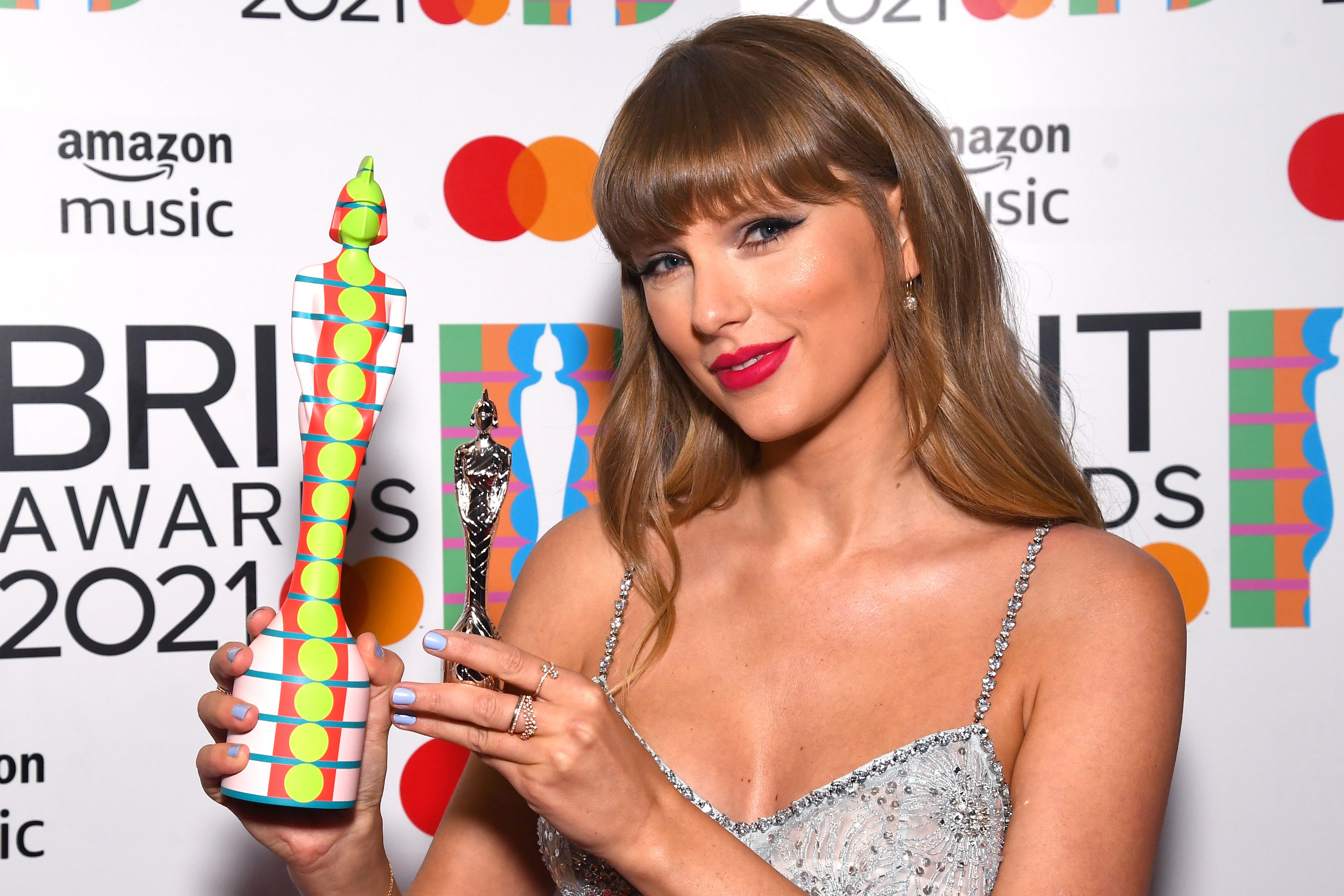 Taylor Swift smiling while holding her Global Icon award during The BRIT Awards 2021