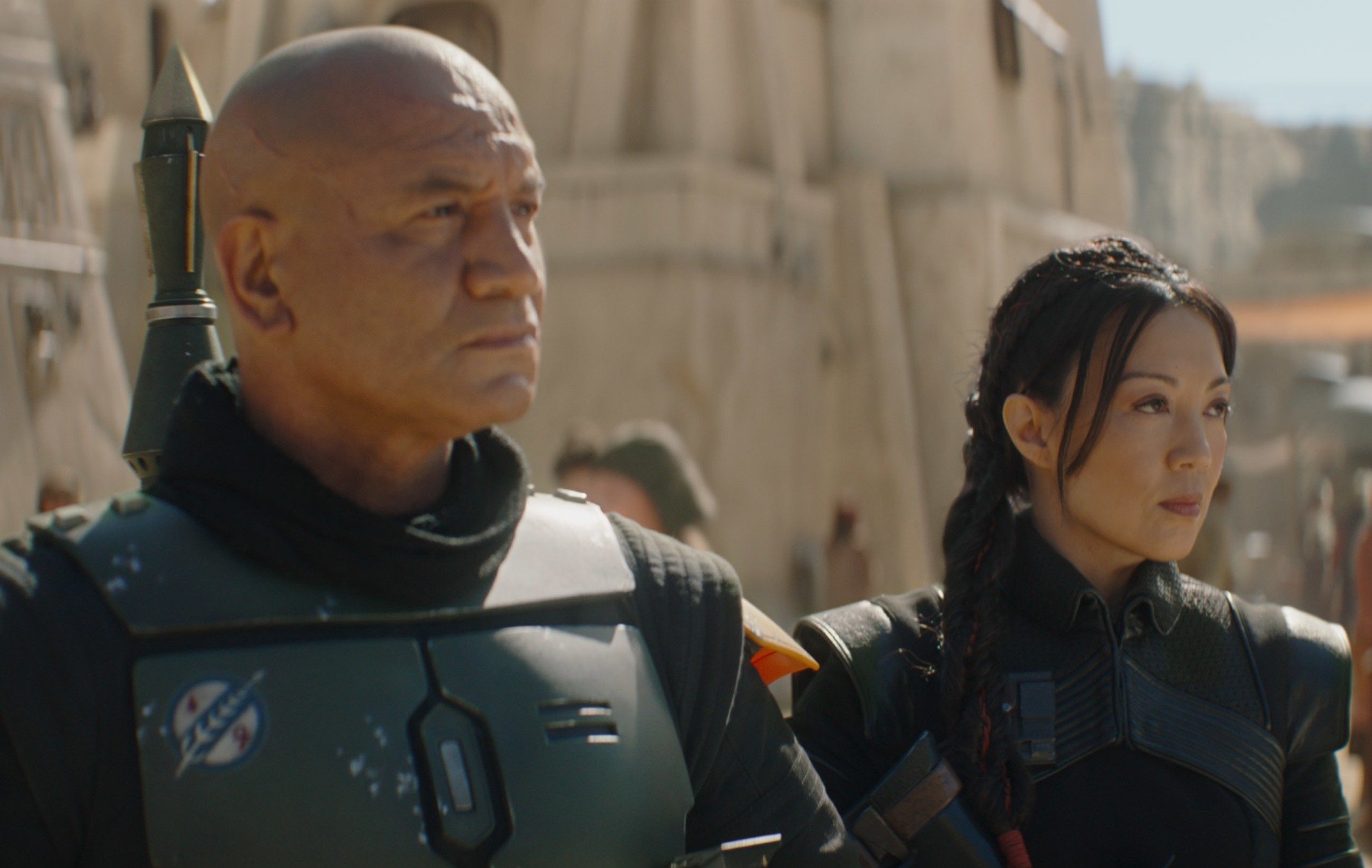 Temuera Morrison and Ming-Na Wen as Boba Fett and Fennec Shand in 'The Book of Boba Fett.' They're standing next to one another and staring at something.