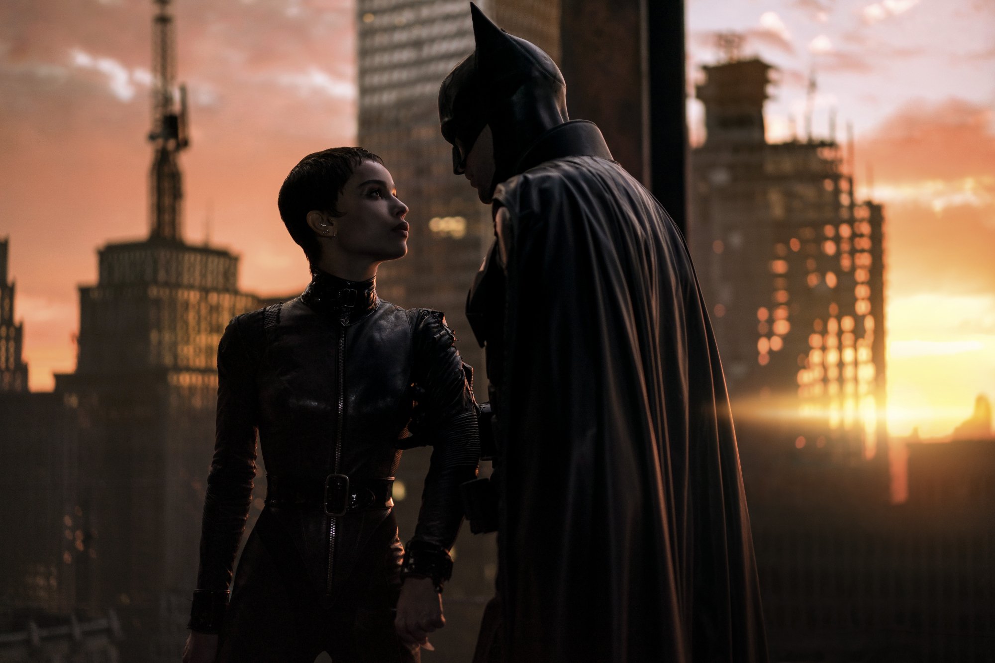 'The Batman' Zoë Kravitz as Selina Kyle_Catwoman and Robert Pattinson as Batman_Bruce Wayne looking at each other in front of a cityscape