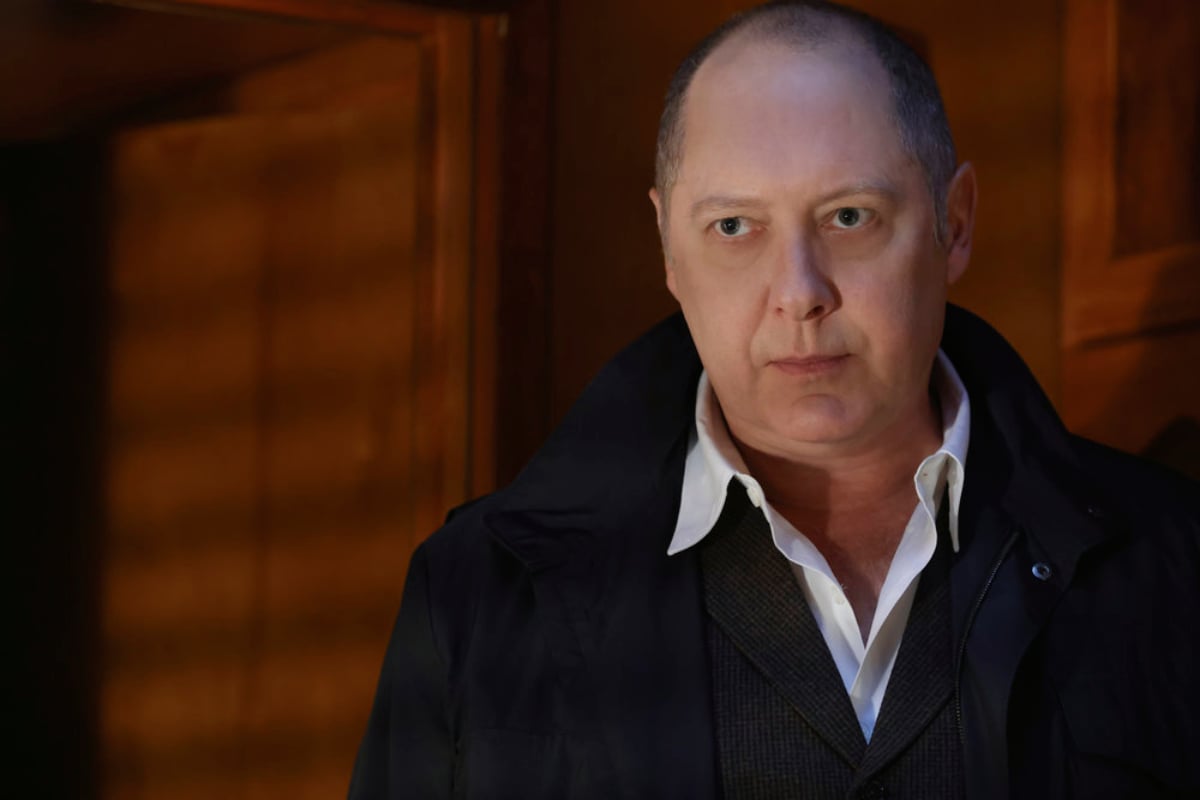James Spader as Raymond Reddington in The Blacklist Season 9. Red wears a white collared shirt and black coat and looks serious.