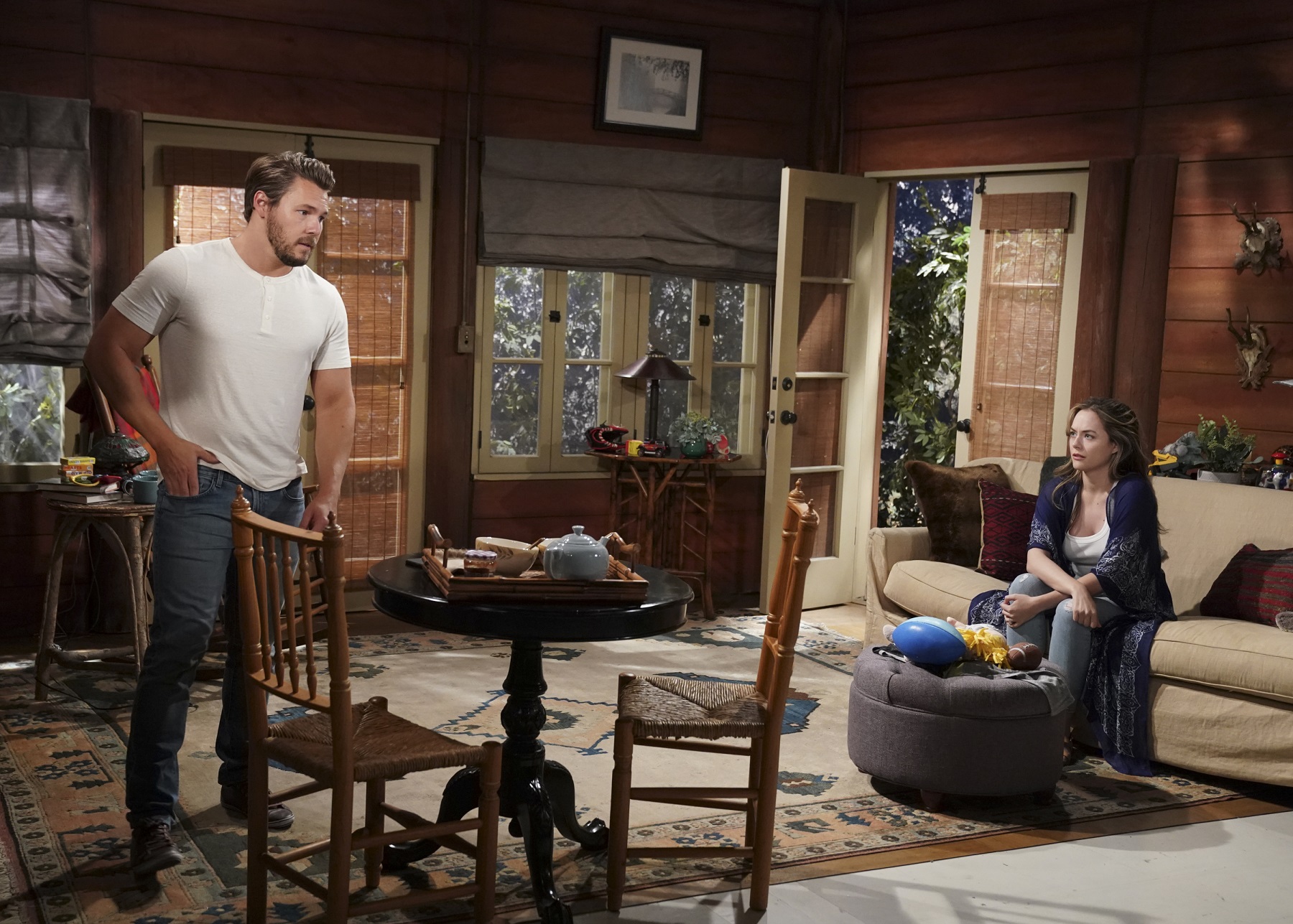 The Bold and the Beautiful stars Scott Clifton, in a white shirt and jeans, and Annika Noelle, in a black duster and sitting on the couch