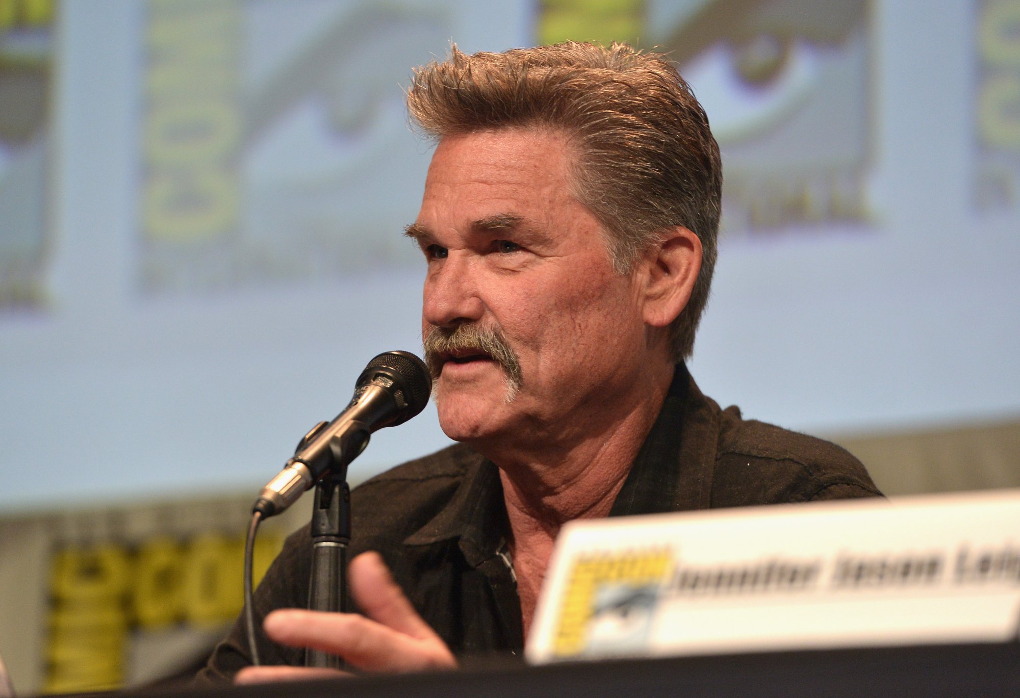 'The Hateful Eight' Kurt Russell talking into a microphone with a name card in front