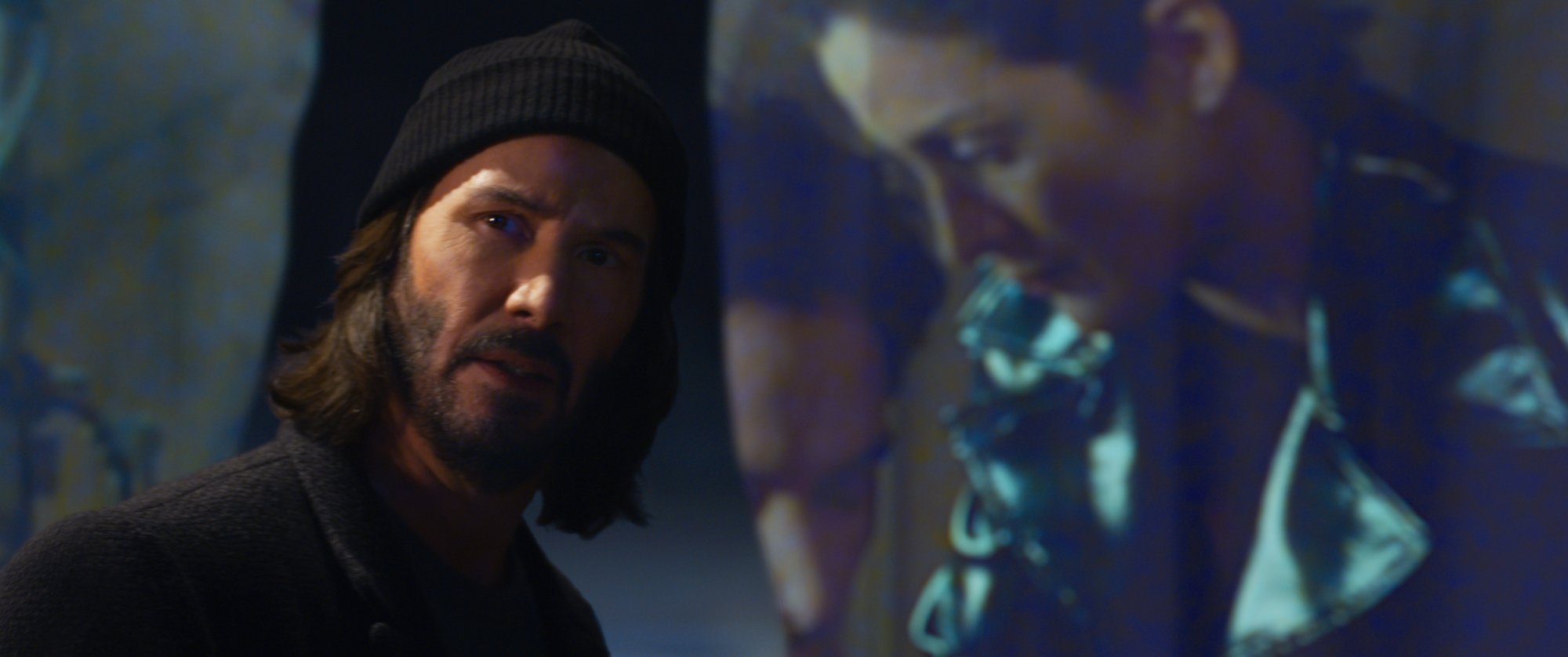 'The Matrix Resurrections' Keanu Reeves as Neo and Carrie-Anne Moss as Trinity wearing a cap in front of a screen