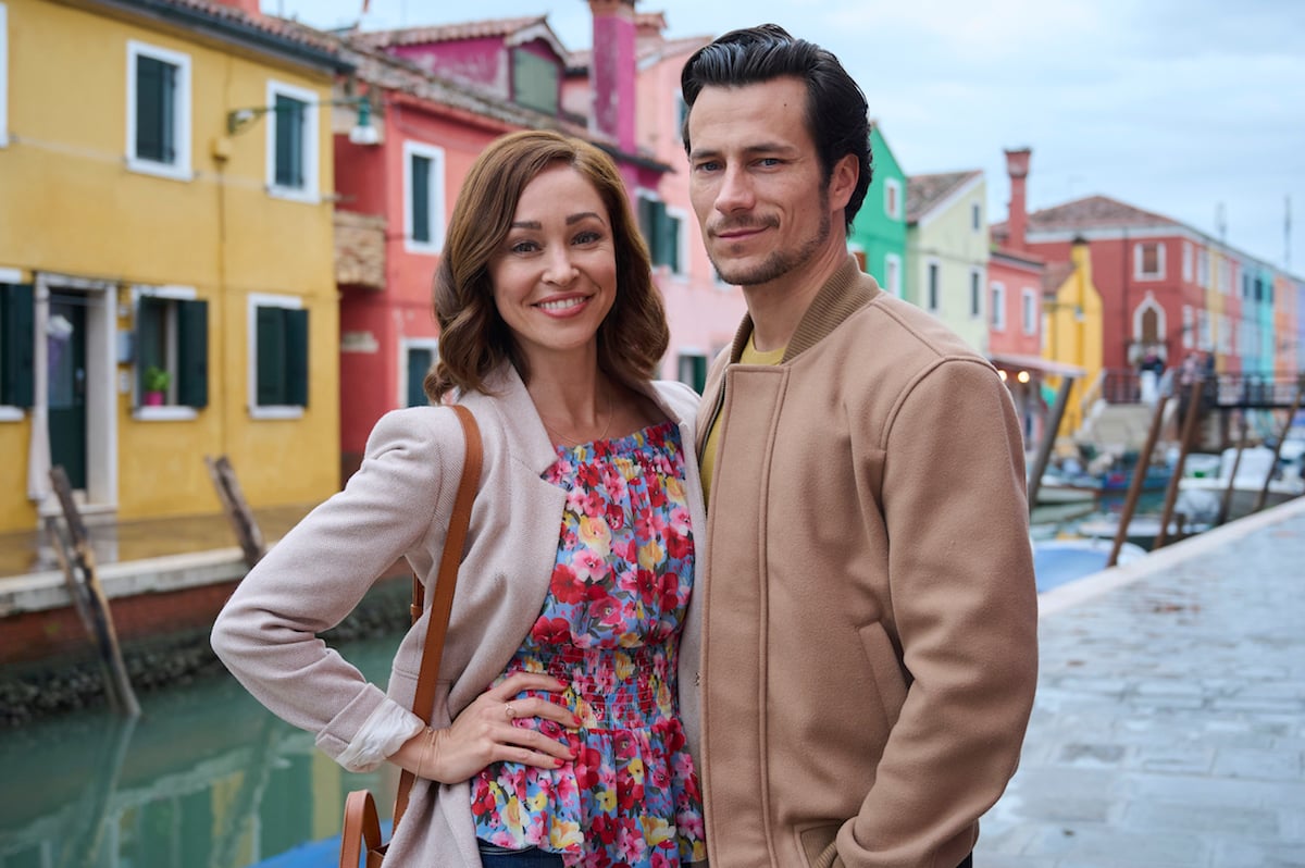 Smiling Autumn Reeser and Paolo Bernardini standing with a canal in the background in 'The Wedding Veil Unveiled'