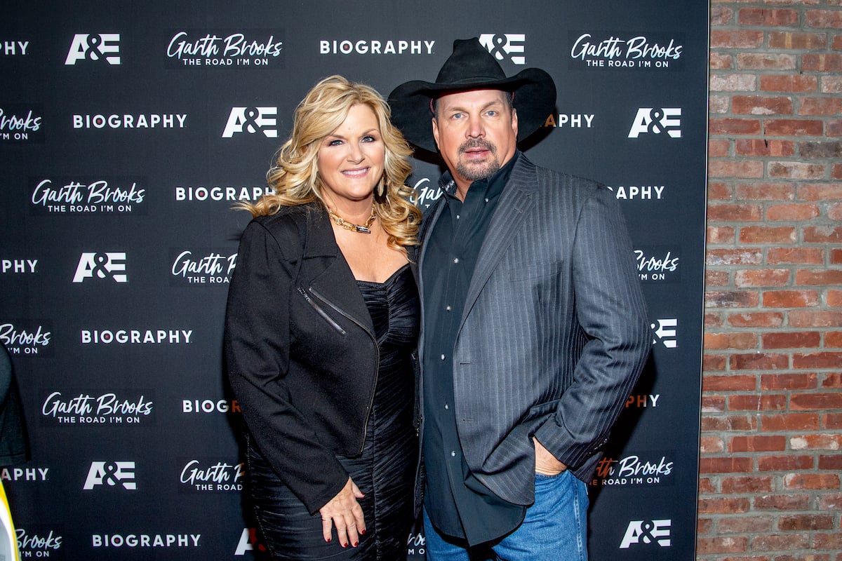 (L-R) Trisha Yearwood and Garth Brooks smiling in front of a black background