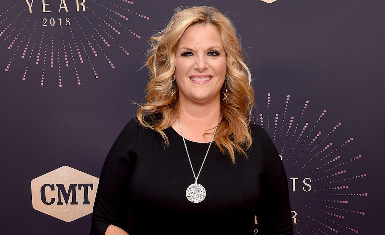 Trisha Yearwood smiles for cameras posing on the red carpet in a black outfit