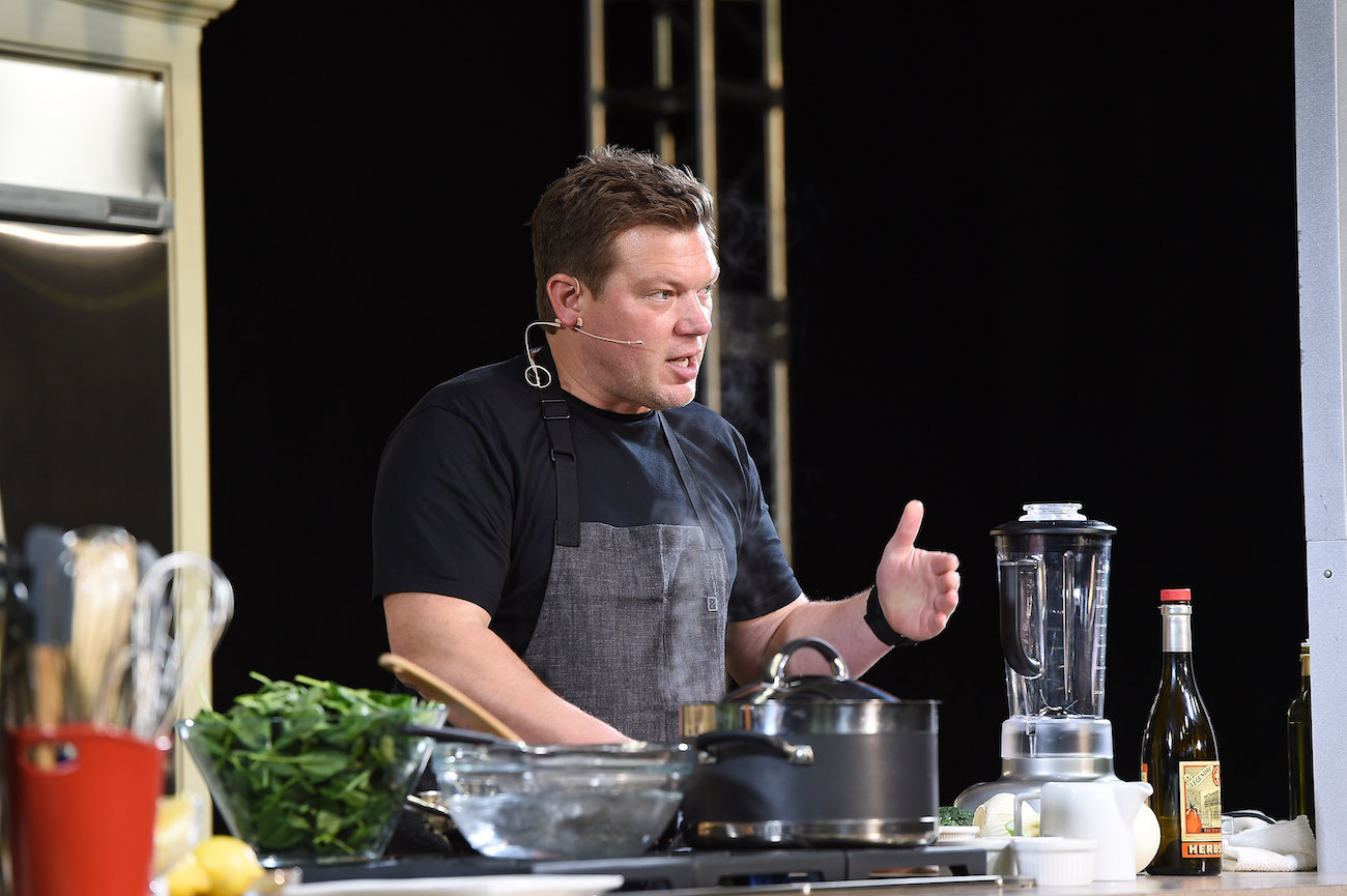 Tyler Florence wears a black shirt and gray apron as he cooks
