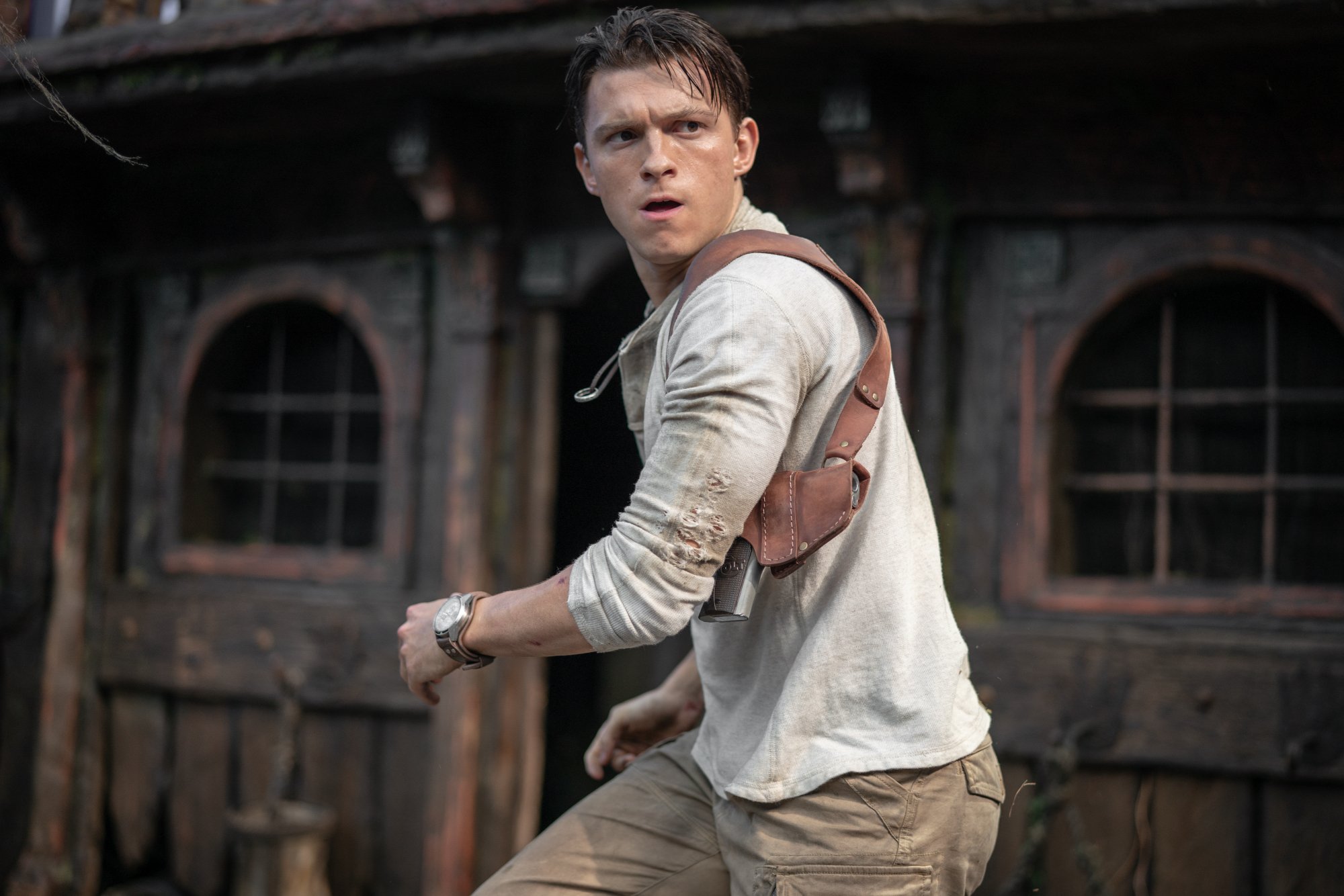 'Uncharted' Tom Holland as Nathan Drake wearing a white shirt and tan pants