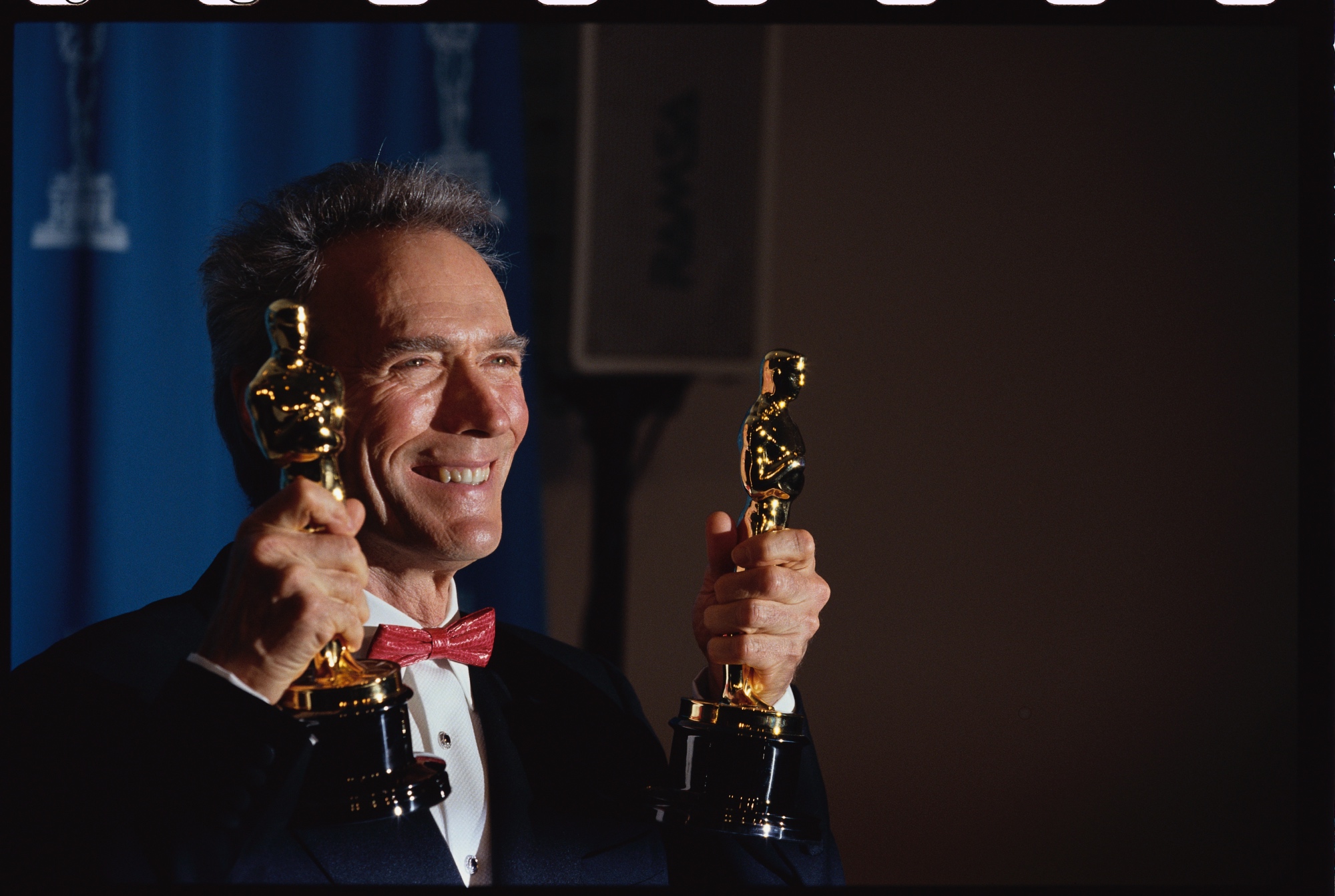 'Unforgiven' filmmaker and actor Clint Eastwood holding up two Oscars