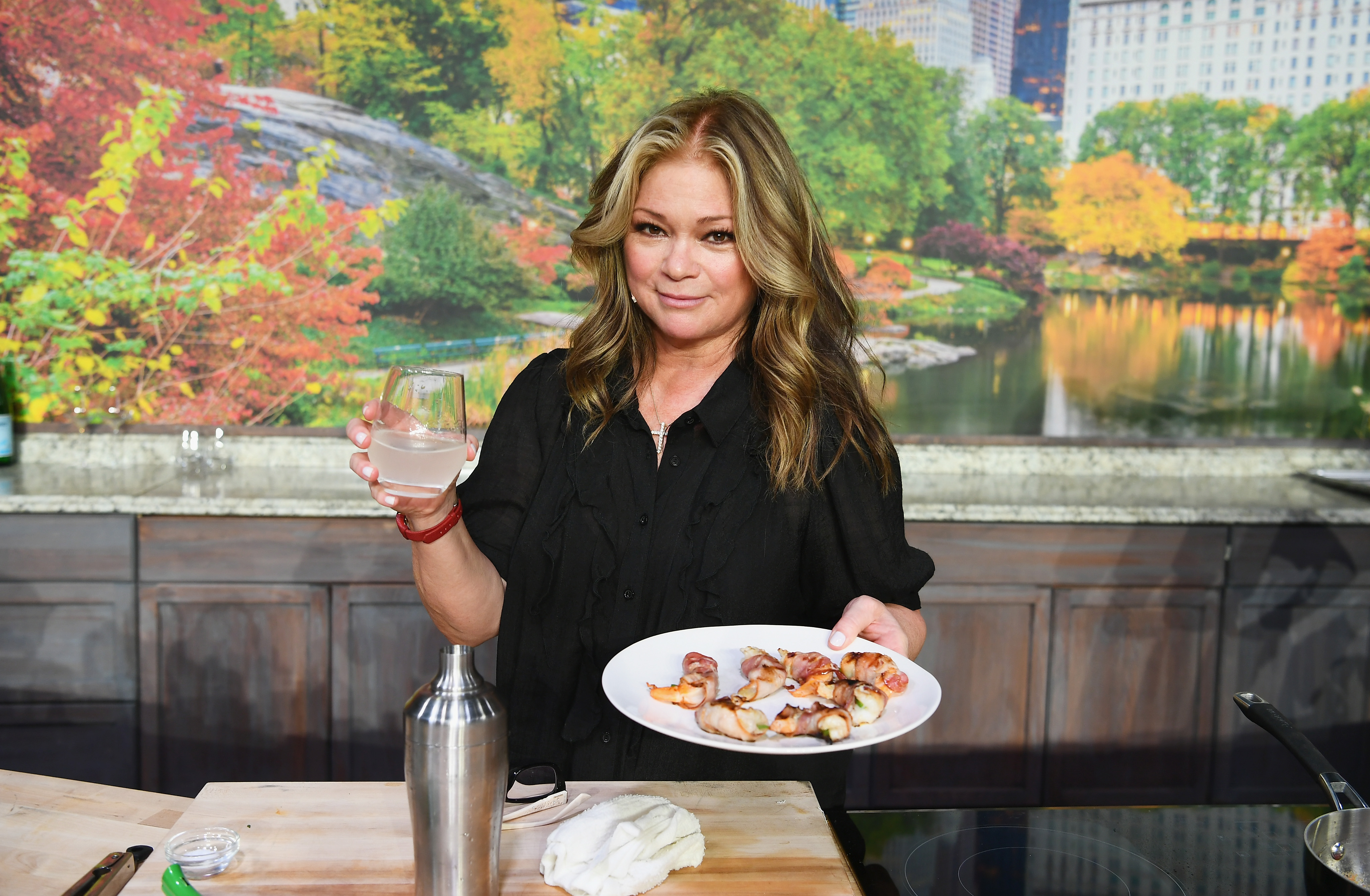 Valerie Bertinelli poses with a plate of food and a drink at a 2018 Food Network event.