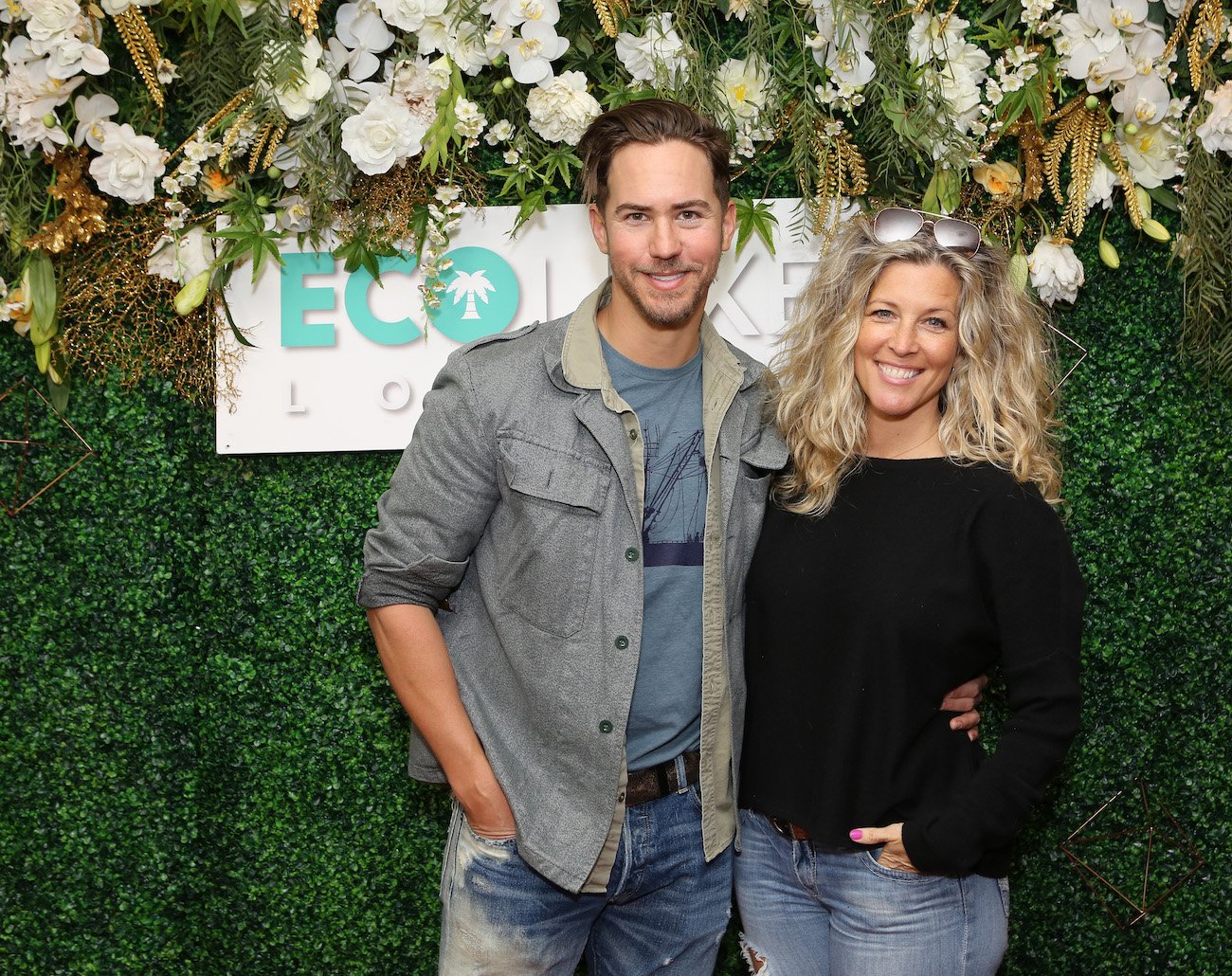 Wes Ramsey and Laura Wright posing next to each other in front of plants