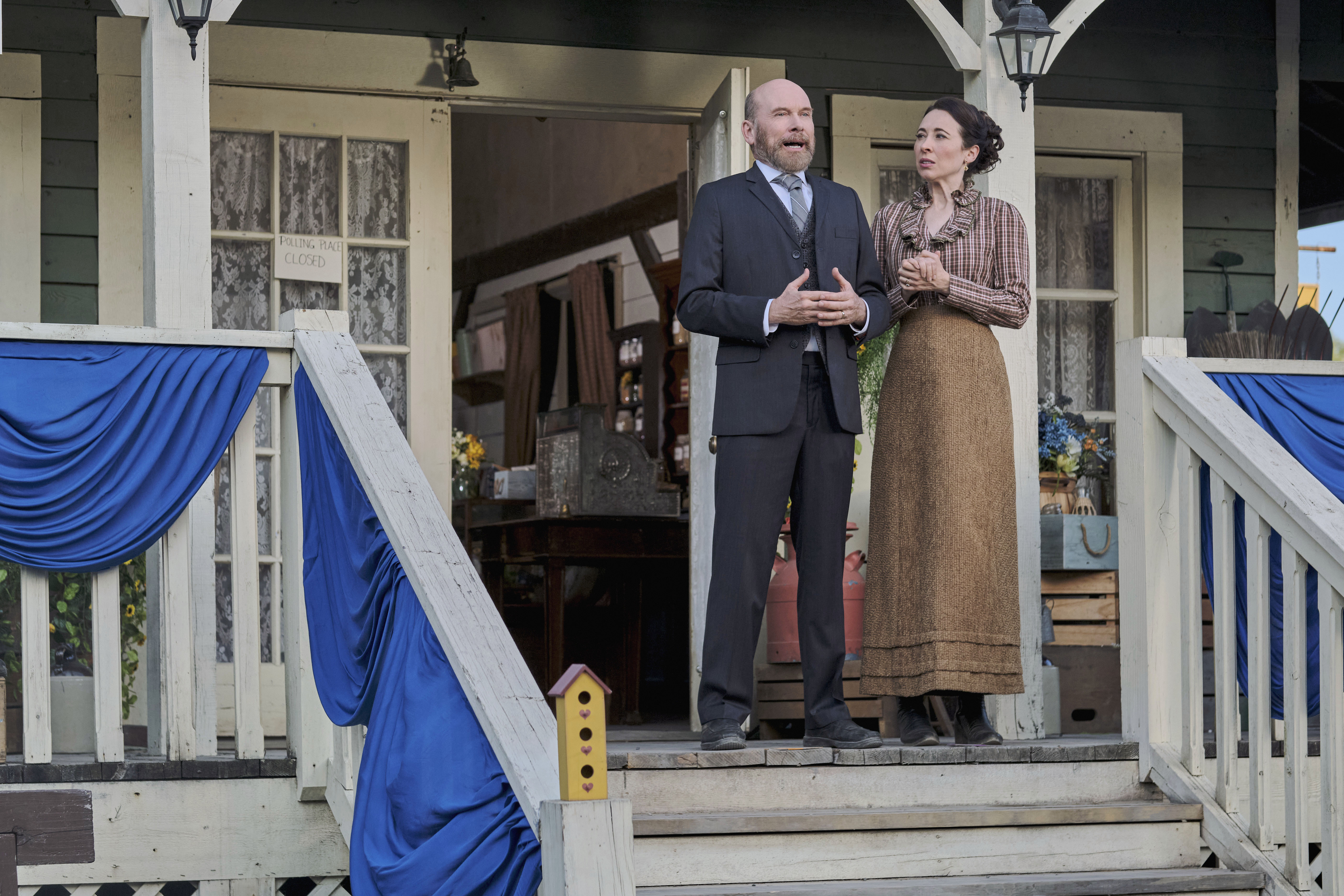 Hrothgar Mathews as Ned and Loretta Walsh as Florence standing on a front porch in 'When Calls the Heart' Season 9