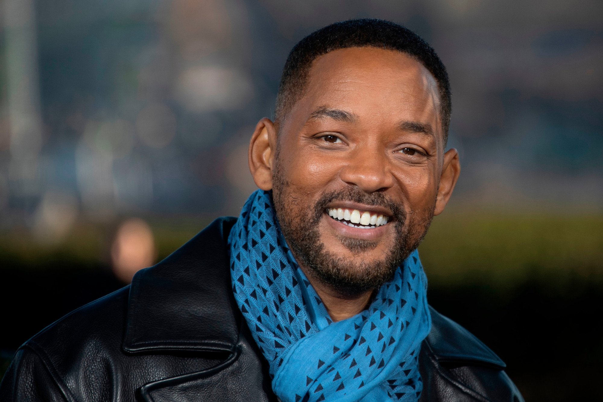 'Suicide Squad' star Will Smith wearing a black jacket and blue scarf and smiling.