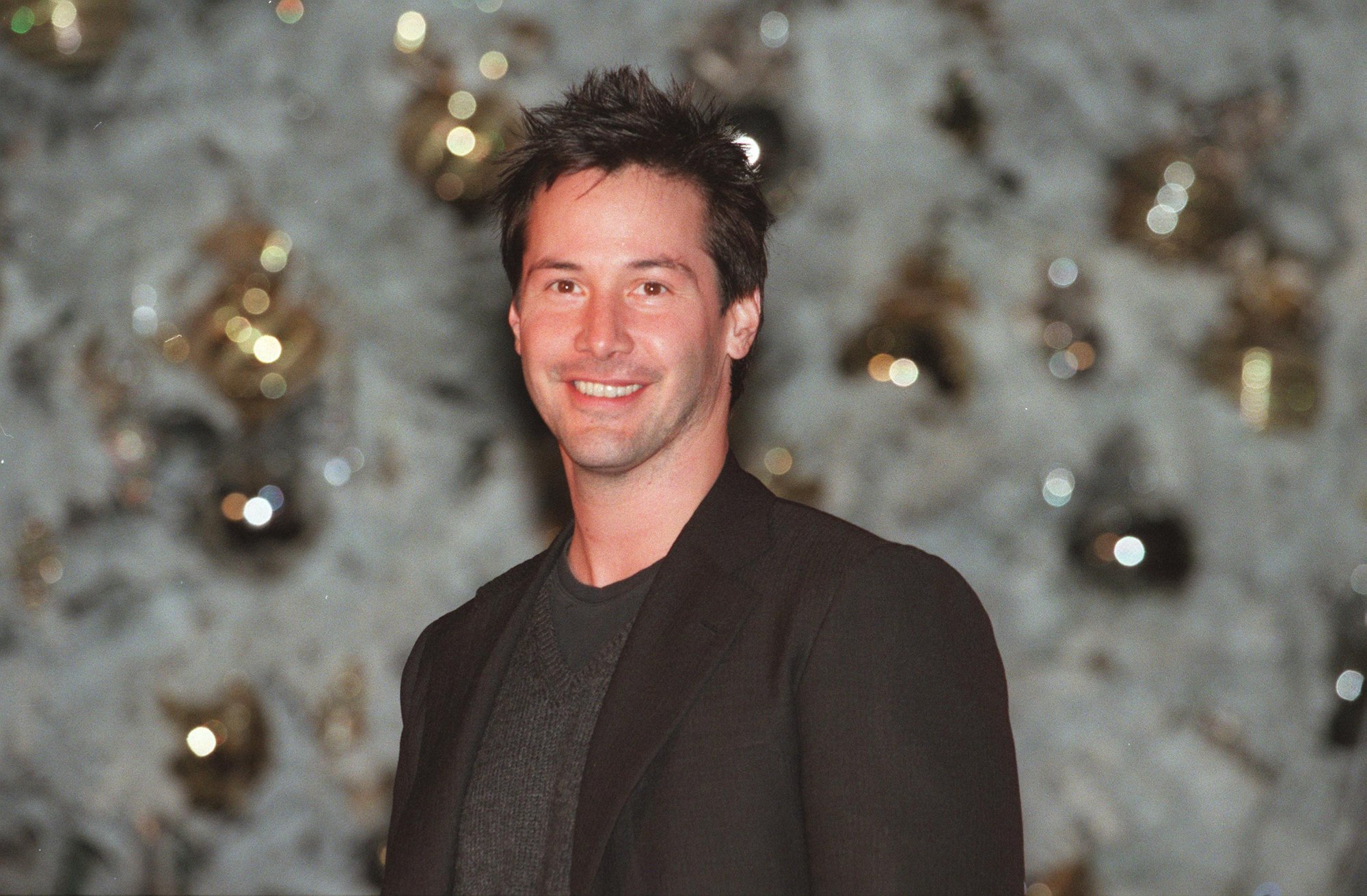 'Wolfboy' actor Keanu Reeves wearing a black suit in front of a Christmas tree