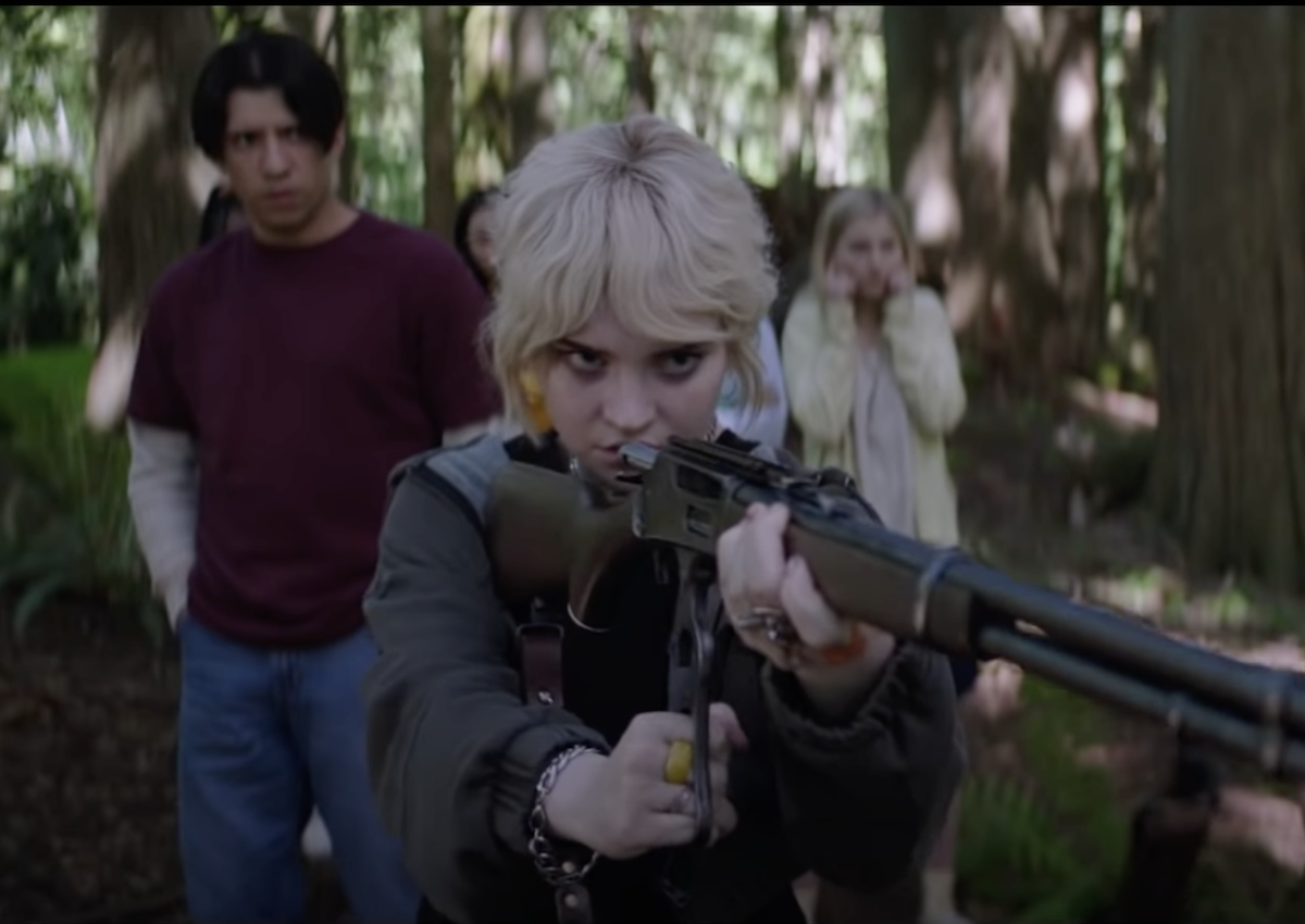 Actor Sophie Thatcher shoots a gun while filming a forest scene in 'Yellowjackets'