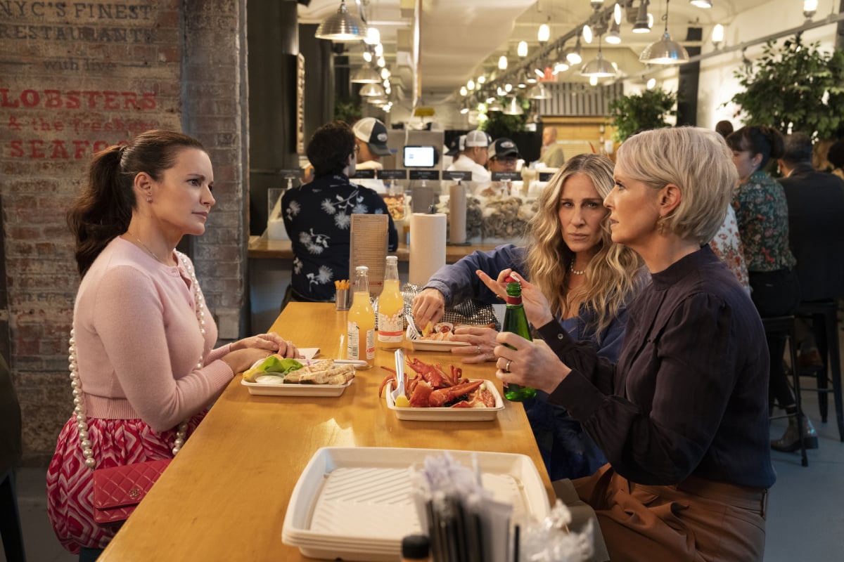 And Just Like That Kristin Davis, Cynthia Nixon, and Sarah Jessica Parker sitting at a table getting ready to eat lobster in an image from the Sex and the City reboot