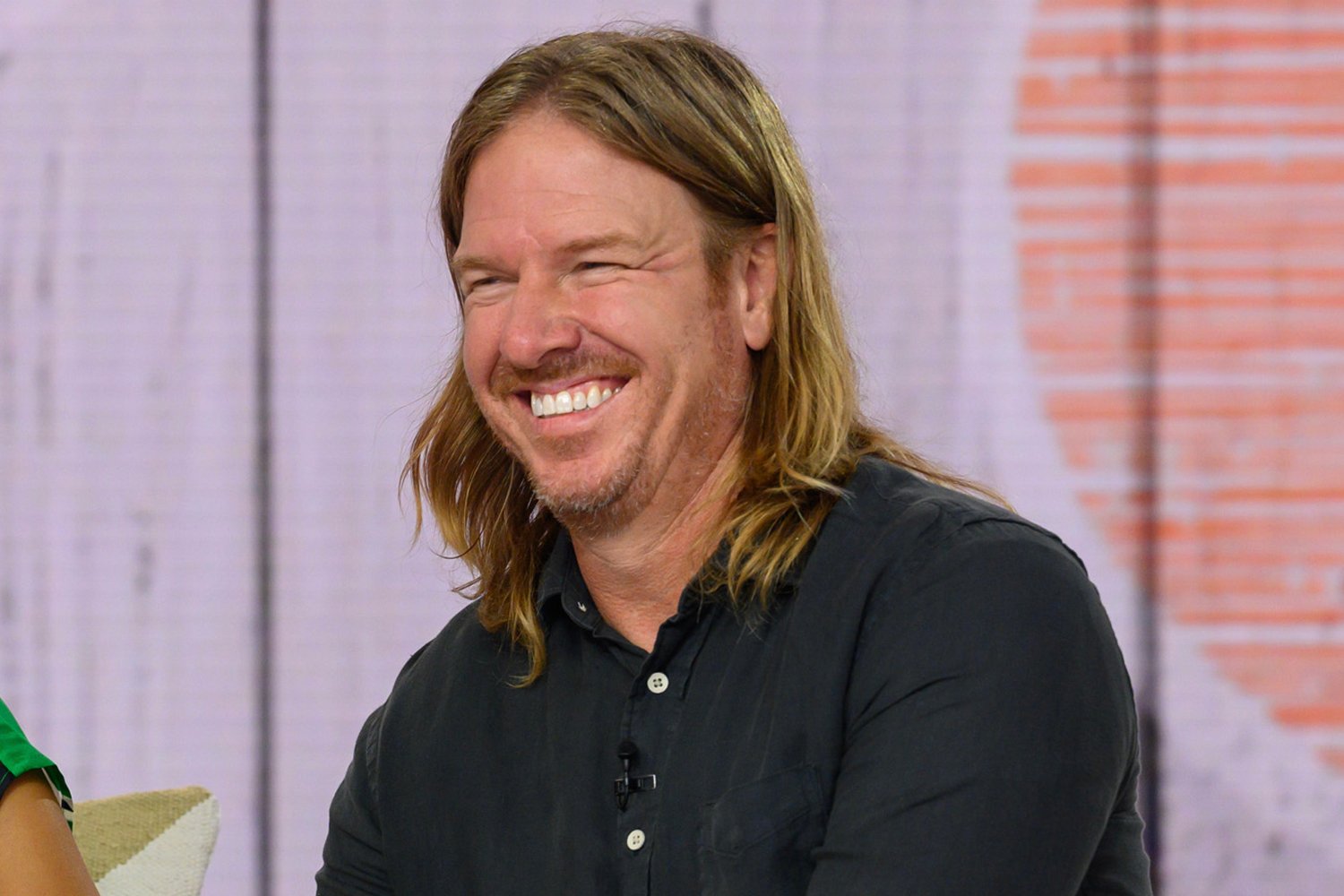 Chip Gaines smiling, long hair, and a button up navy shirt