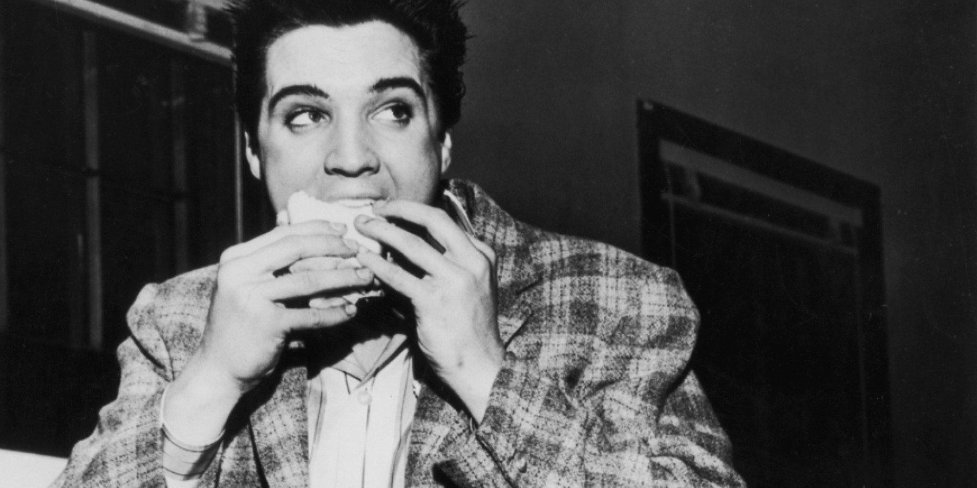 Elvis Presley eating a sandwich.