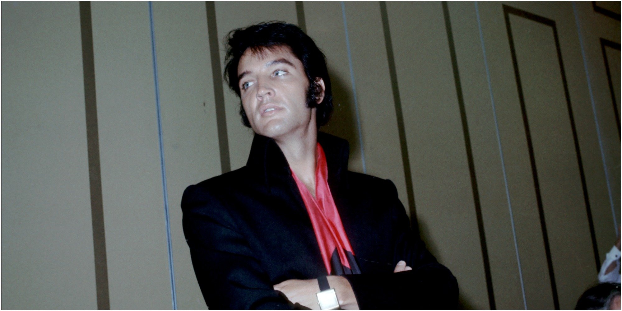 Elvis Presley poses in a black outfit for photographers.