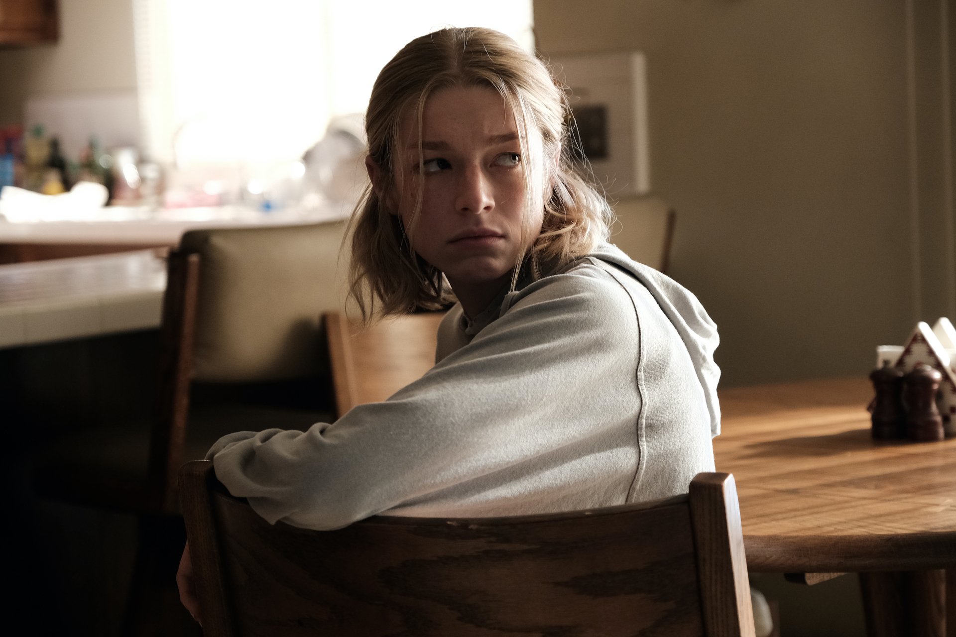 Jules (Hunter Schafer) sits at Rue's kitchen table in 'Stand Still Like the Hummingbird' episode of 'Euphoria'