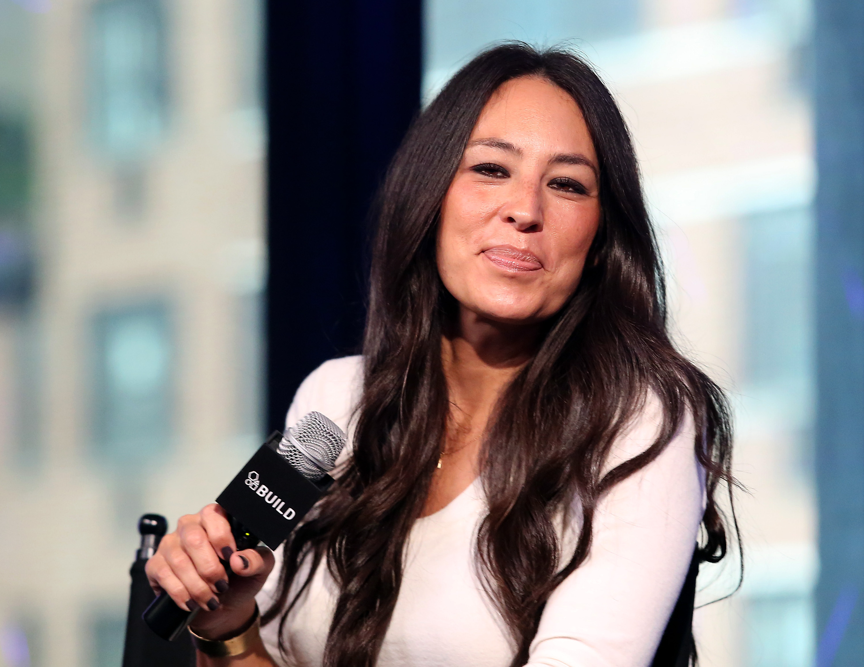 Joanna Gaines holds a microphone and smiles